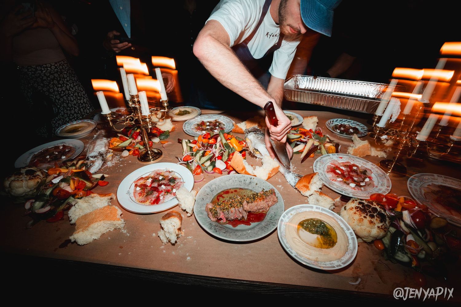 Multiple plates of food and appetizers arranged on a table with decorative candles.