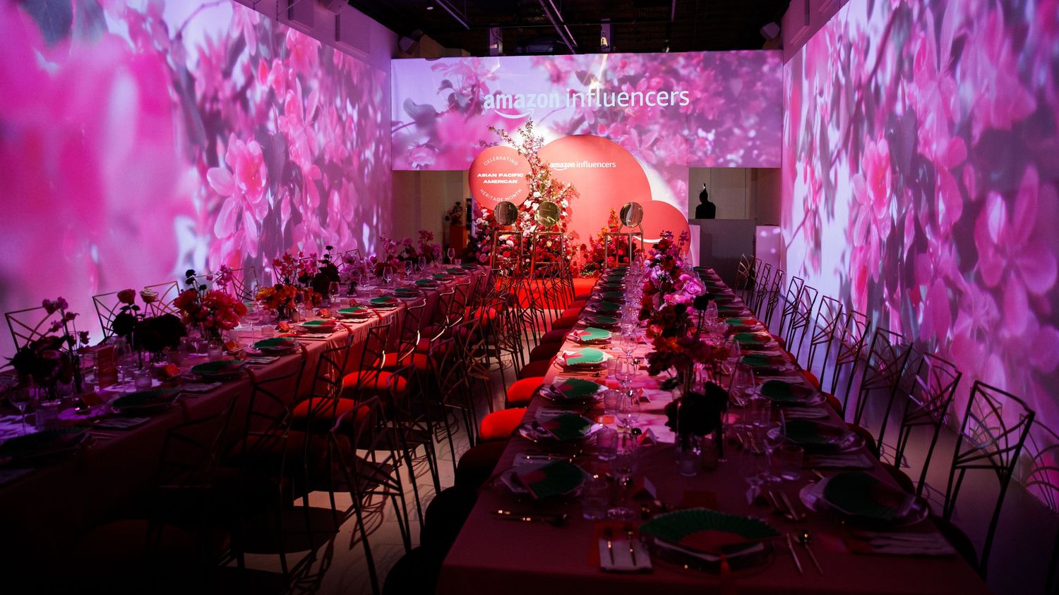 Modern dining hall with pink projected floral patterns on walls and long banquet tables.