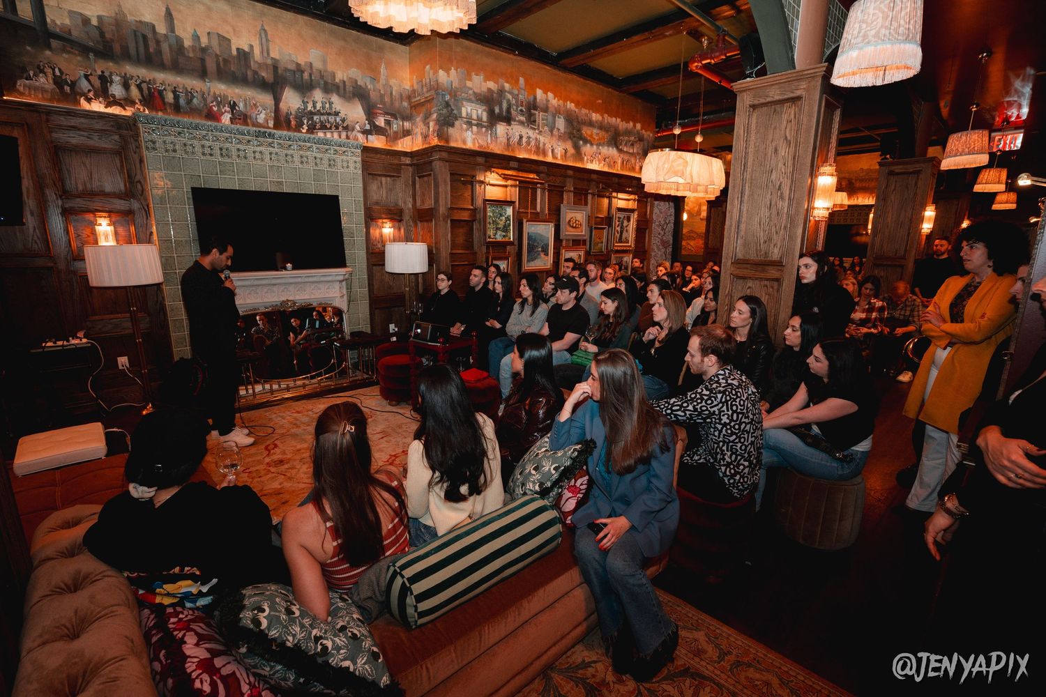 Crowded venue with decorative wall murals and hanging lamps creating ambient atmosphere.