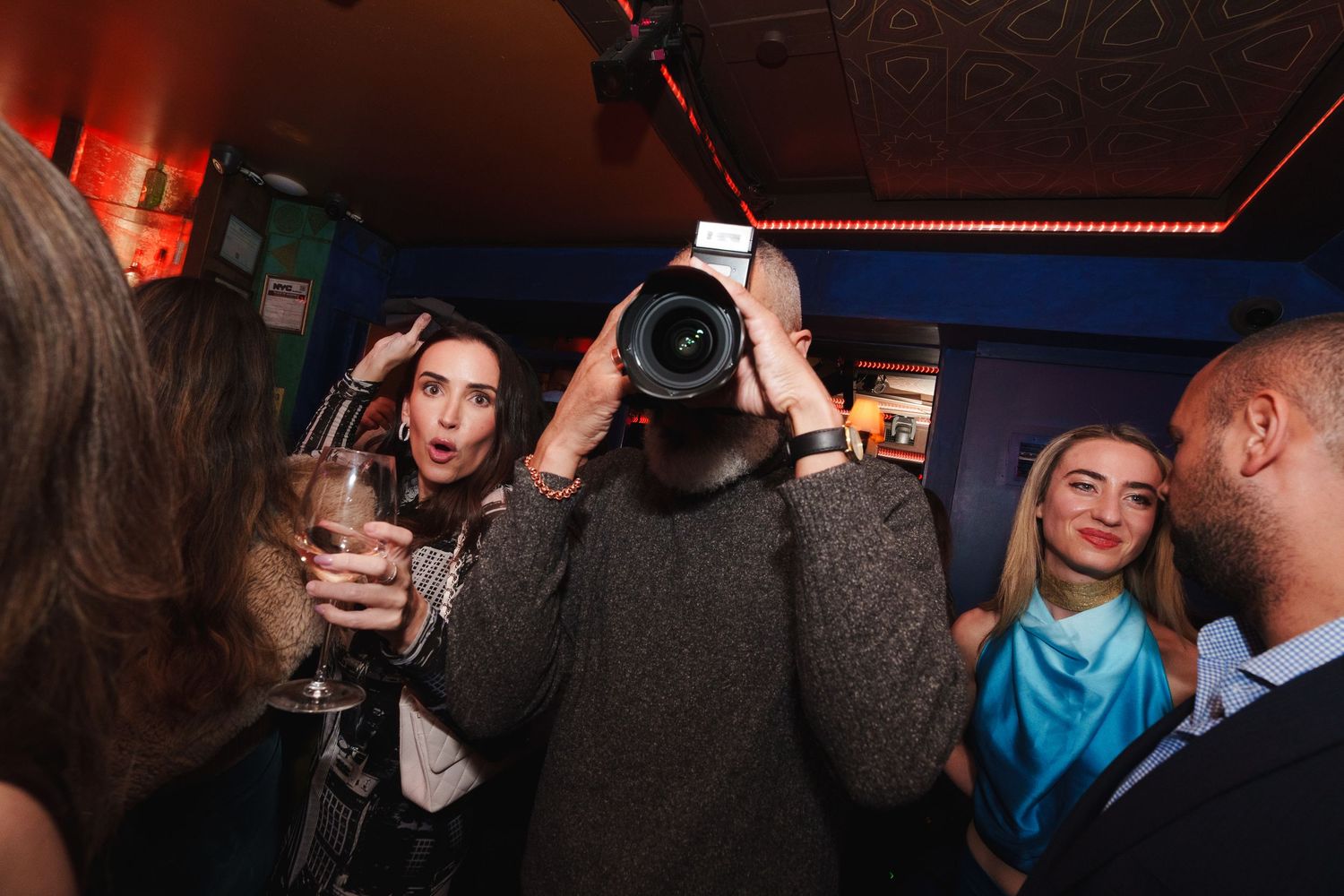 Nightclub scene with photographer taking pictures among party crowd.