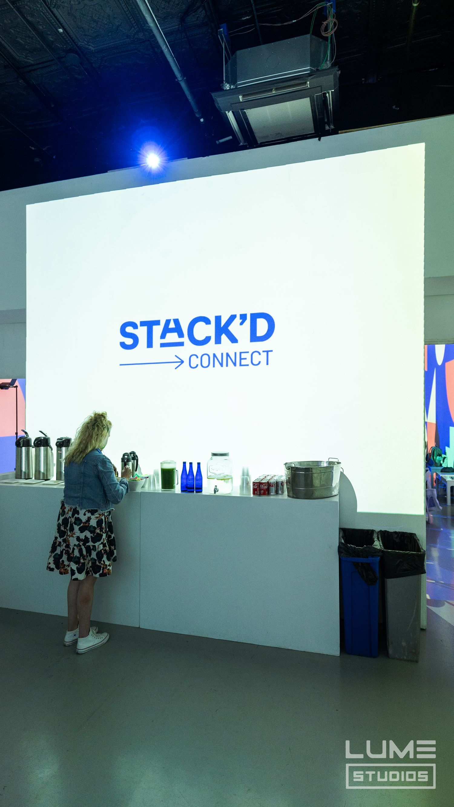 Stack'd Connect branded event space with refreshment counter and illuminated logo display.