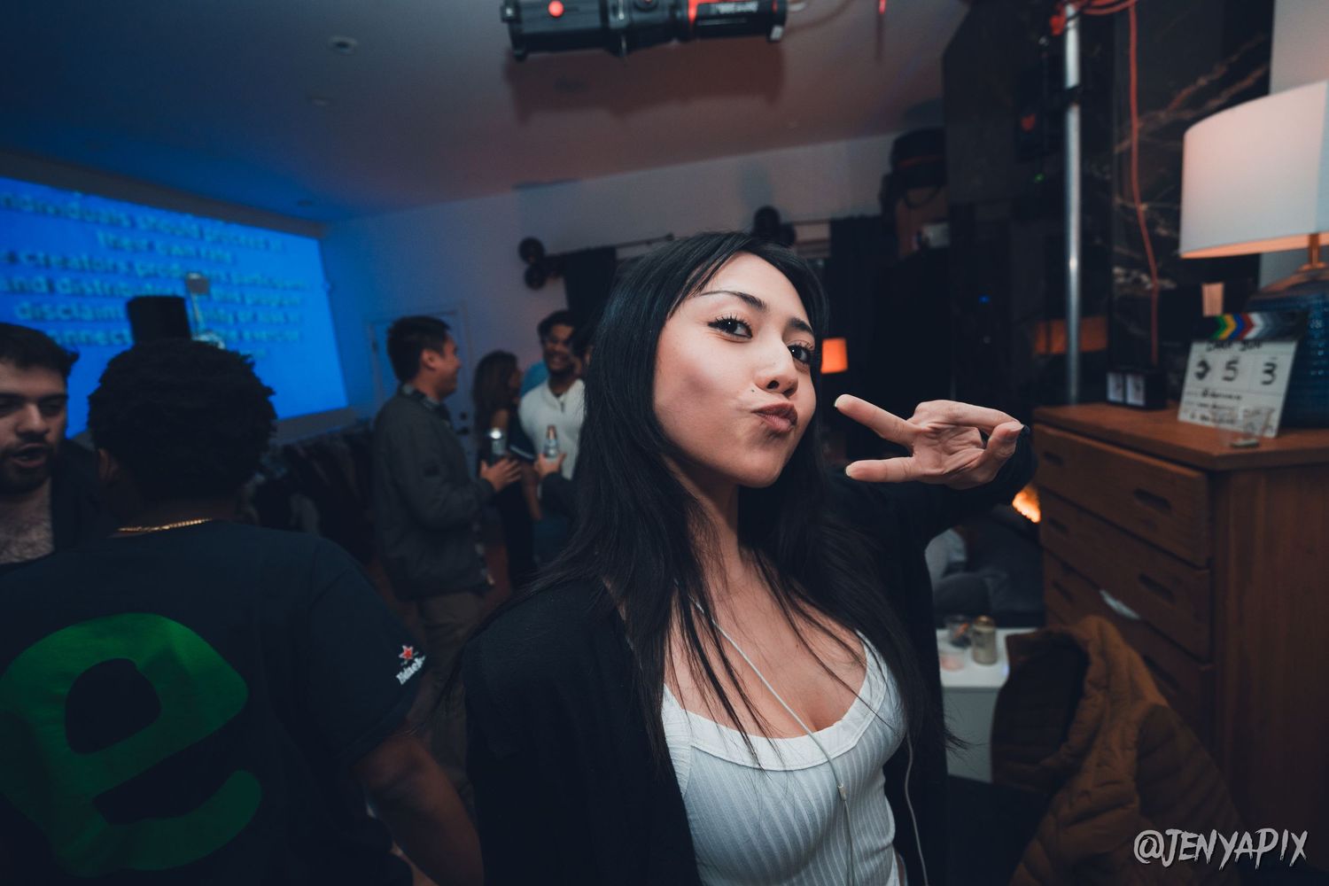 Person in white top posing at a dimly lit nightclub or bar venue.
