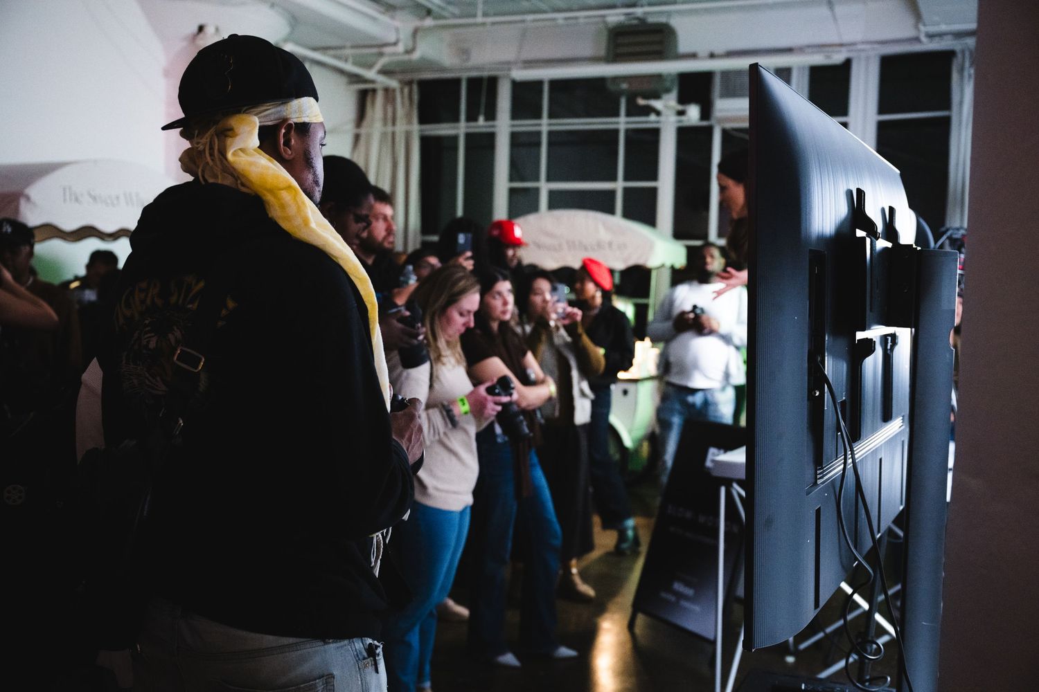 People gather around photography equipment at an indoor event space.