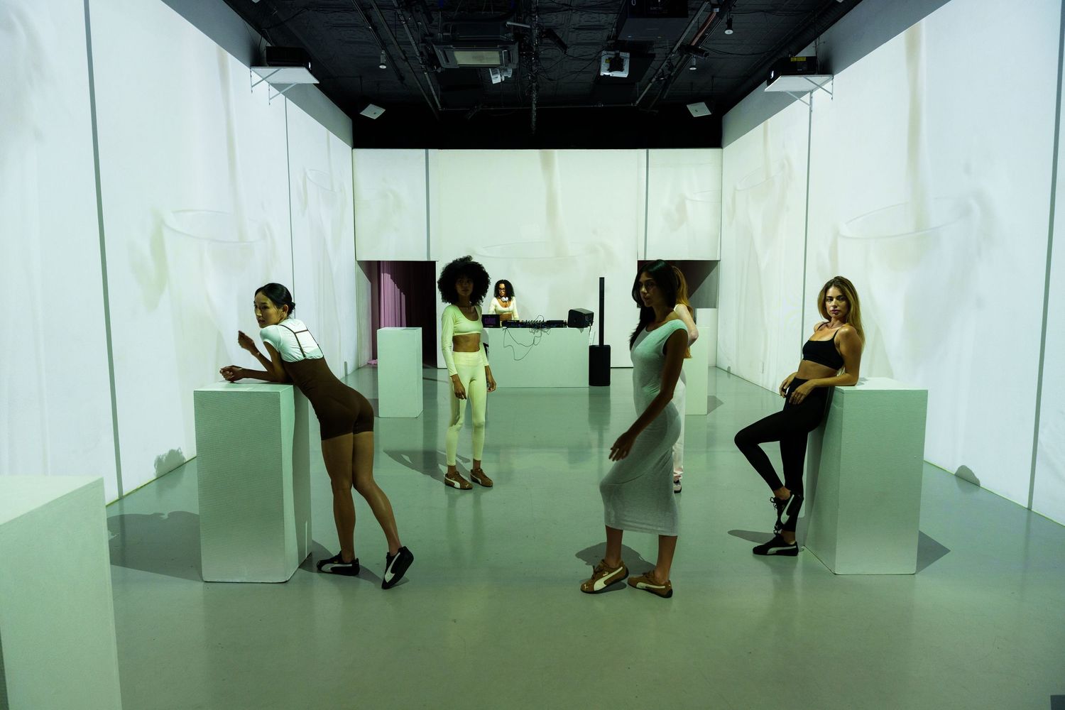 People interact with illuminated white cubes in a contemporary art installation at a modern gallery space.