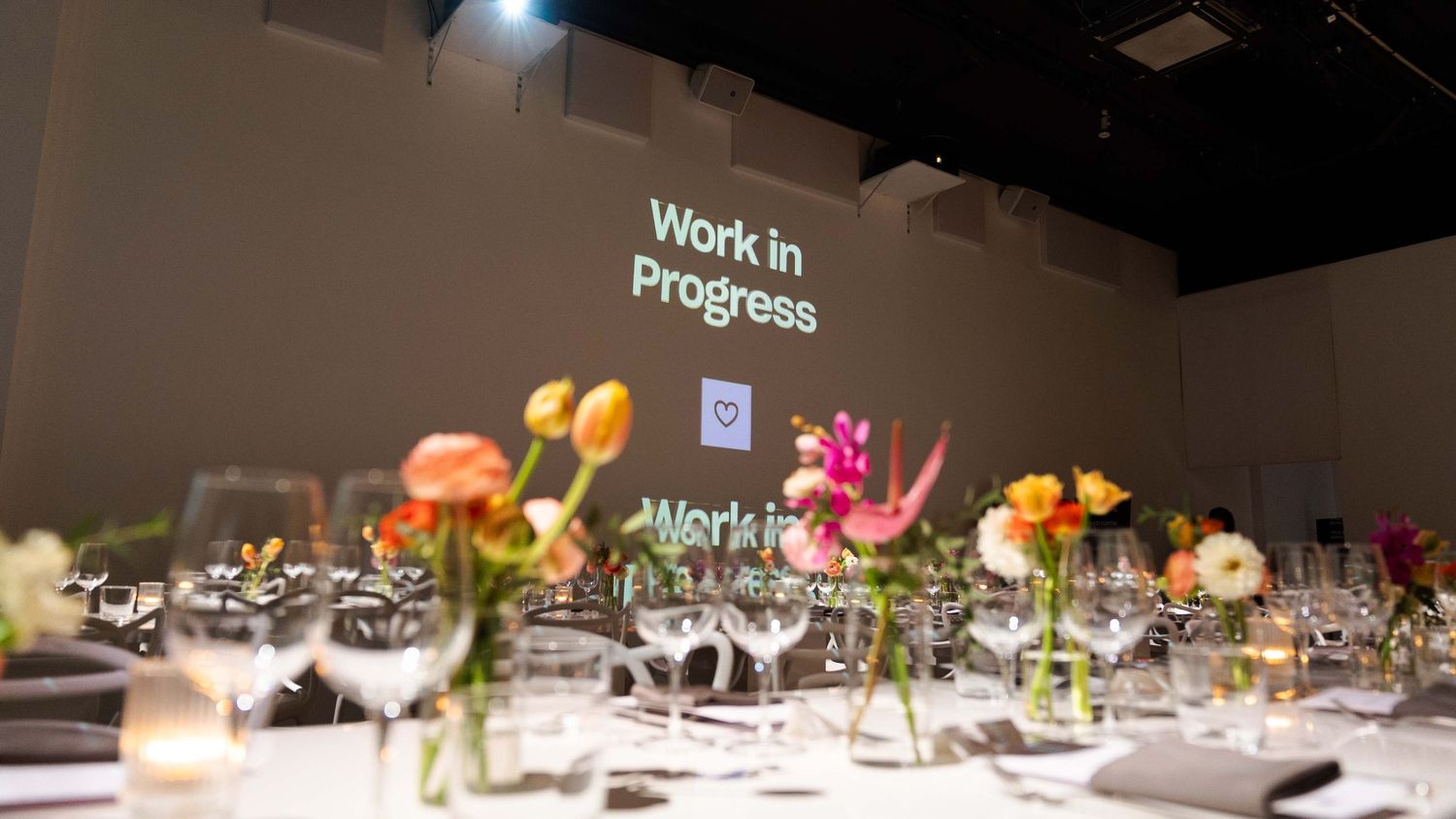 Elegant table setting with colorful flowers and 'Work in Progress' projection display.