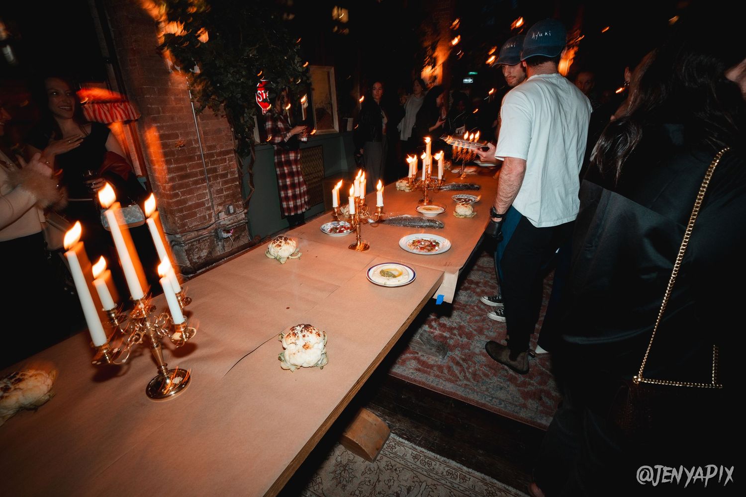 A dimly lit table set with burning candles creating an intimate dining atmosphere.