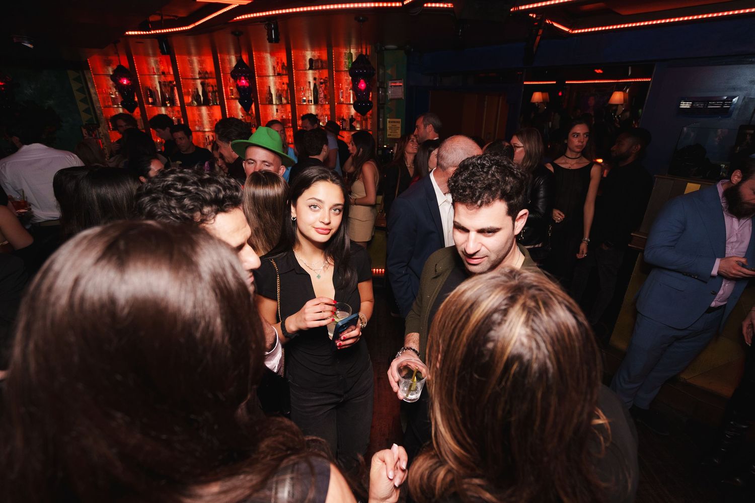 Groups of people mingling and socializing at a dark nightclub event.