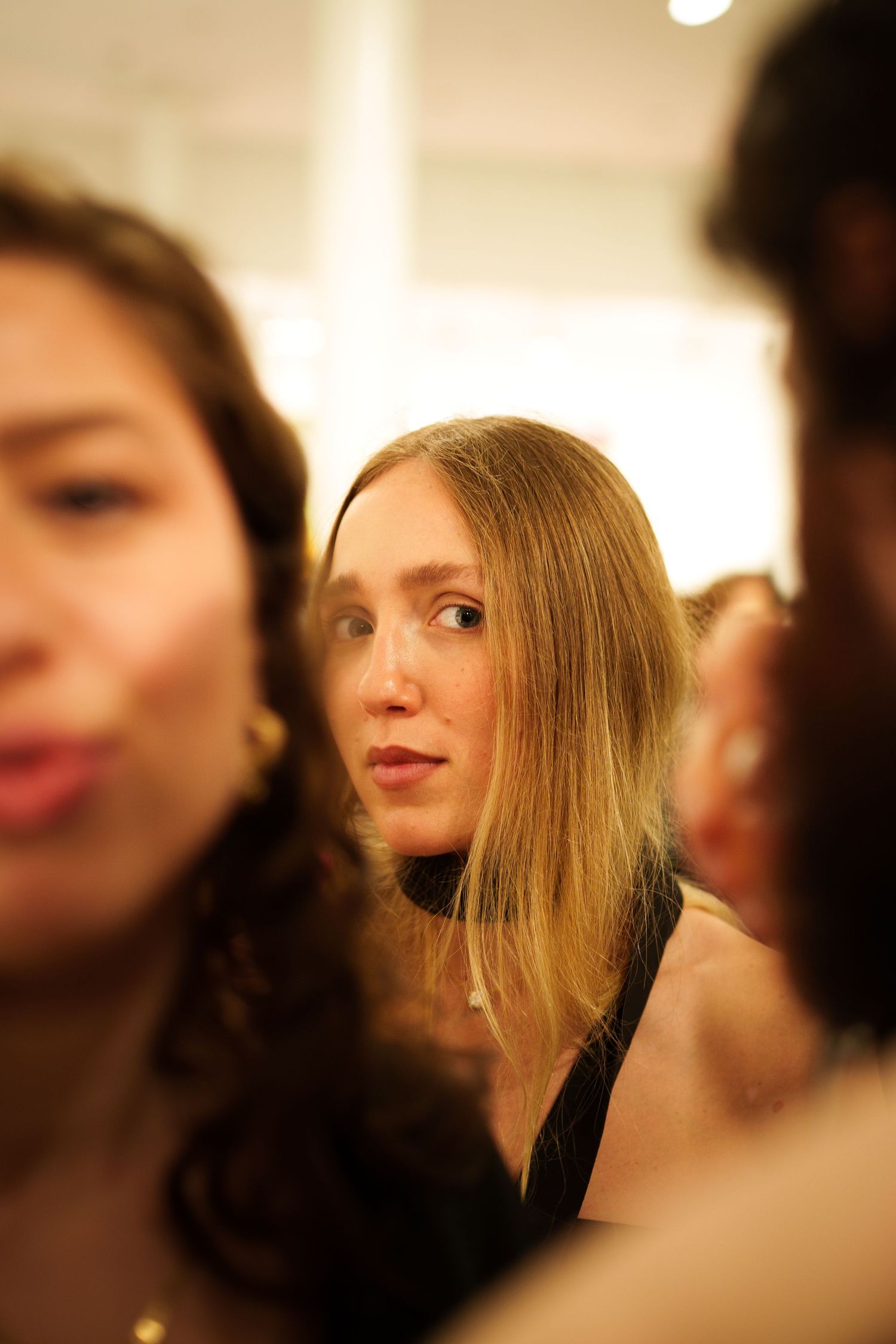 Candid shot of gallery attendees in crowd at evening art event.