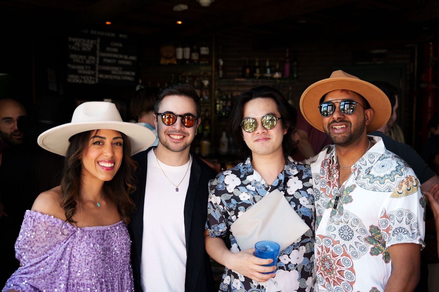 Group of friends in summer attire gathered outside a bar or cafe.