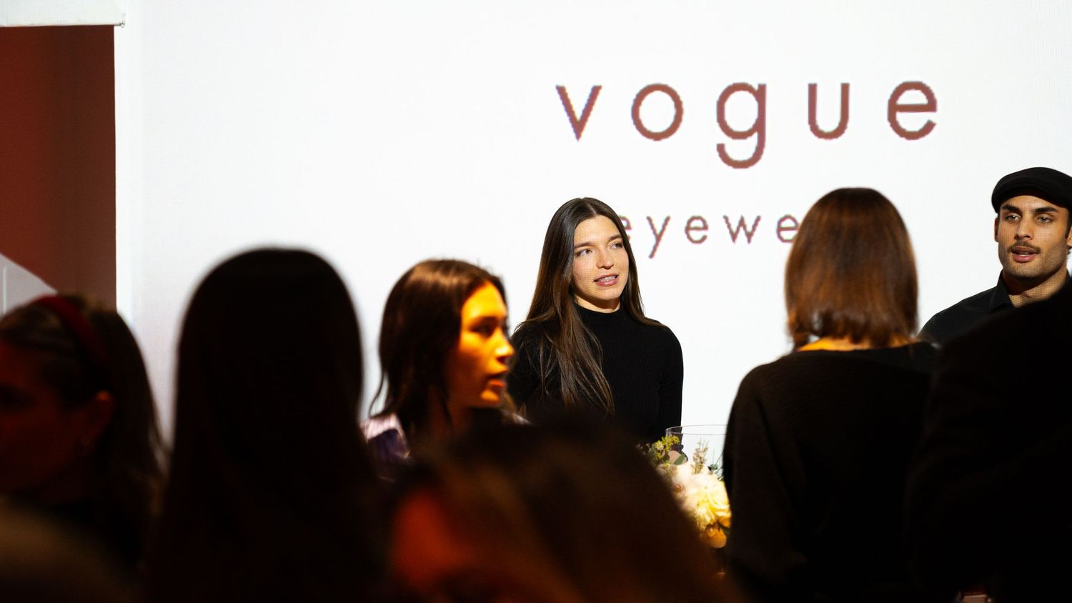 Vogue eyewear presentation with attendees viewing display against white backdrop.