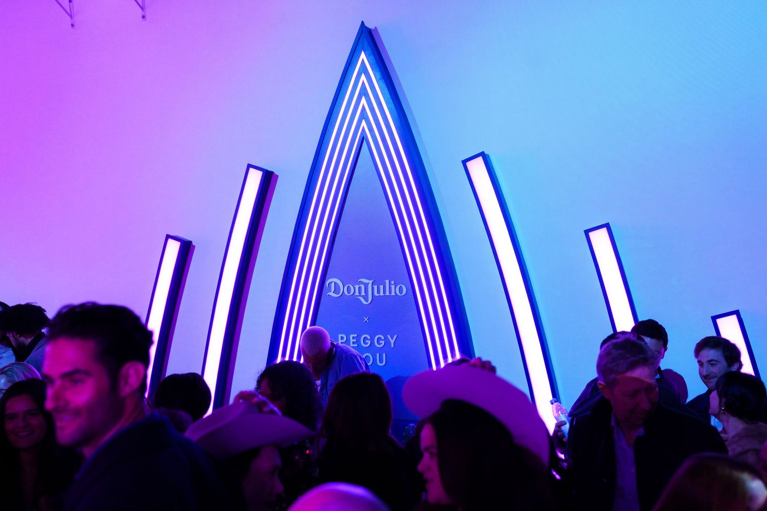 Concert crowd gathered under a blue geometric light installation.