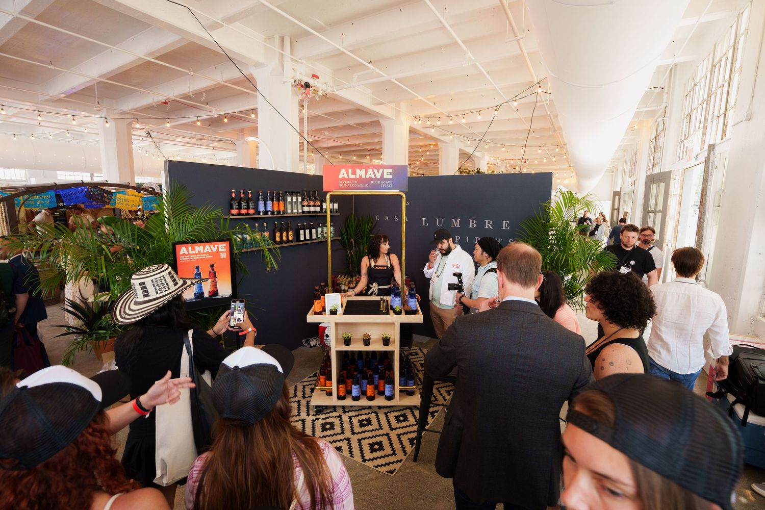 People gathered at a brand activation event with bar setup and tropical plants.