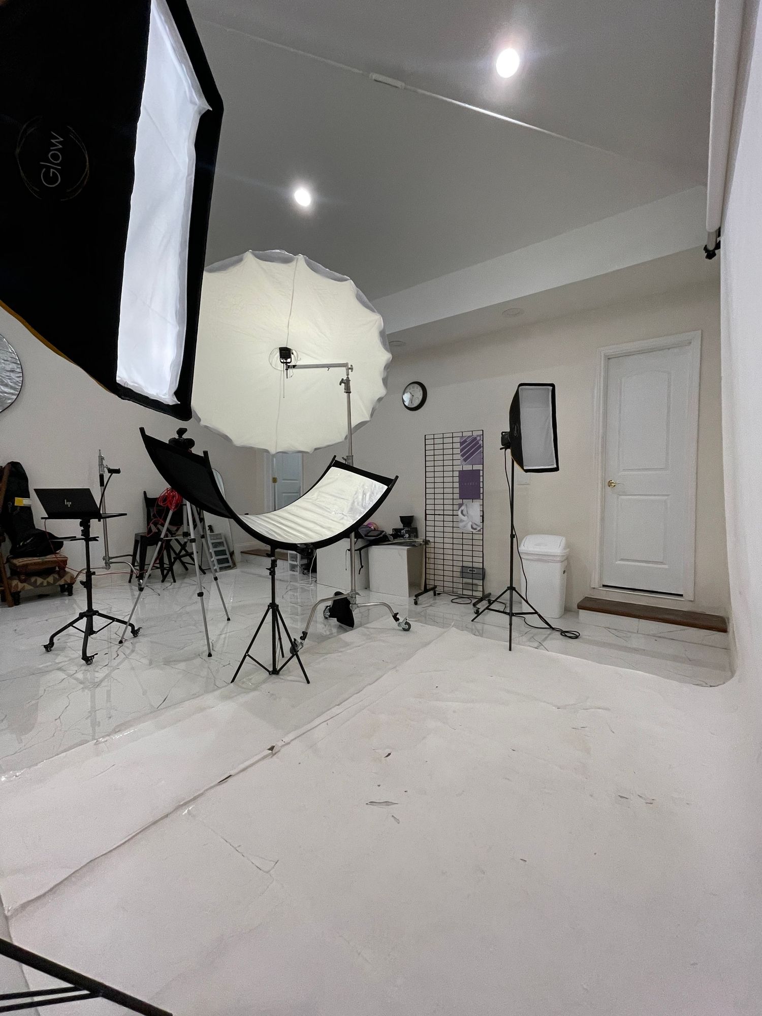 Empty photo studio with lighting equipment and white seamless backdrop setup.