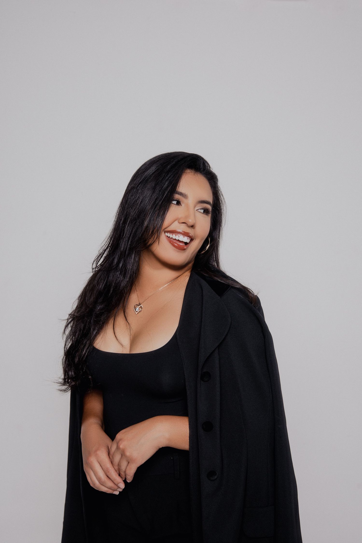 A woman in black clothing poses against a white background in a series of expressive portraits.