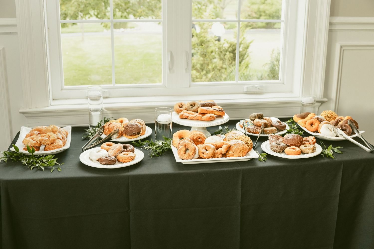 A long buffet table with white plates filled with various foods sits in front of bright windows in a dining room. Located in Bellbrook, Ohio