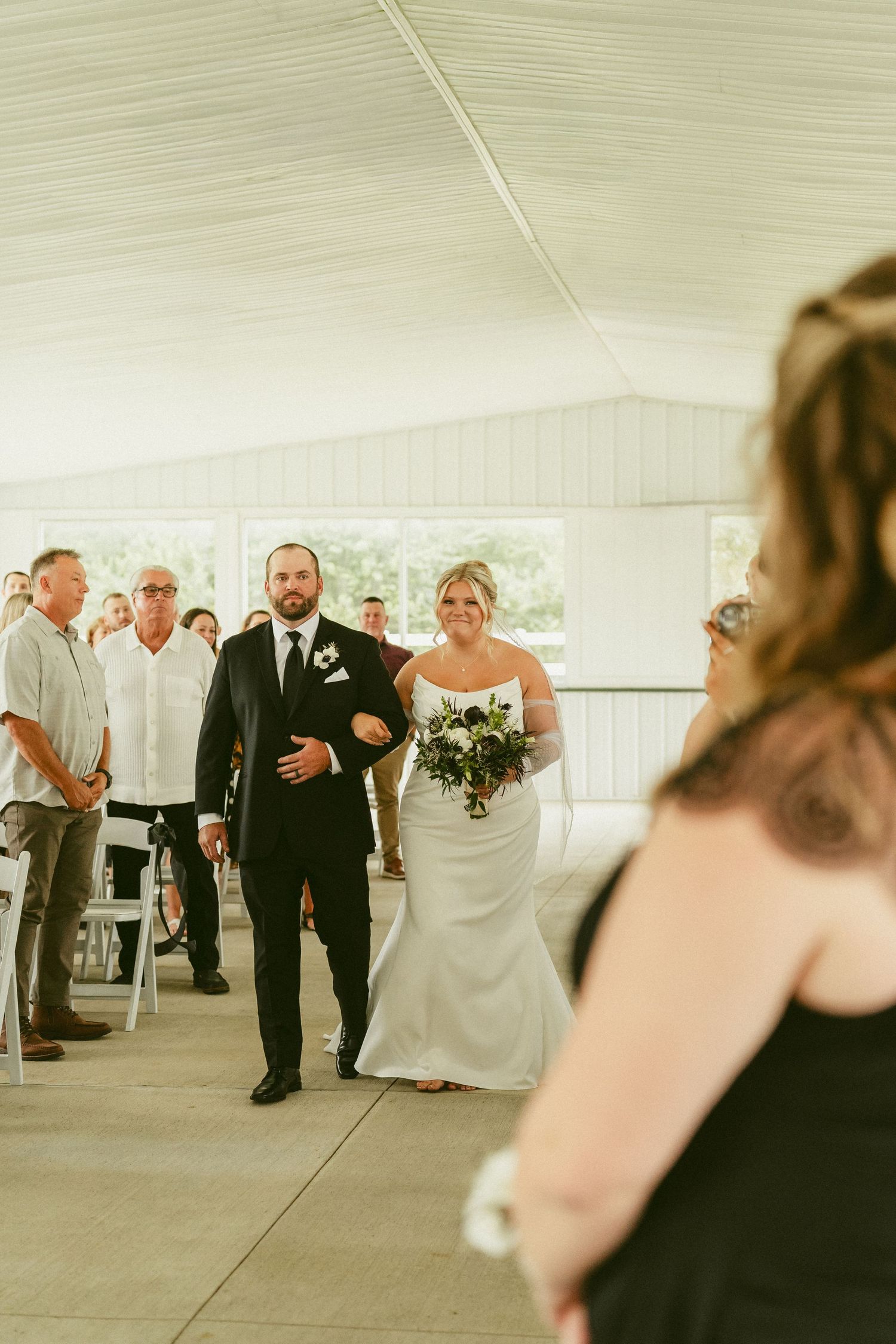 Wedding guests celebrating under a white tent at an outdoor ceremony. Located in Bellbrook, Ohio.