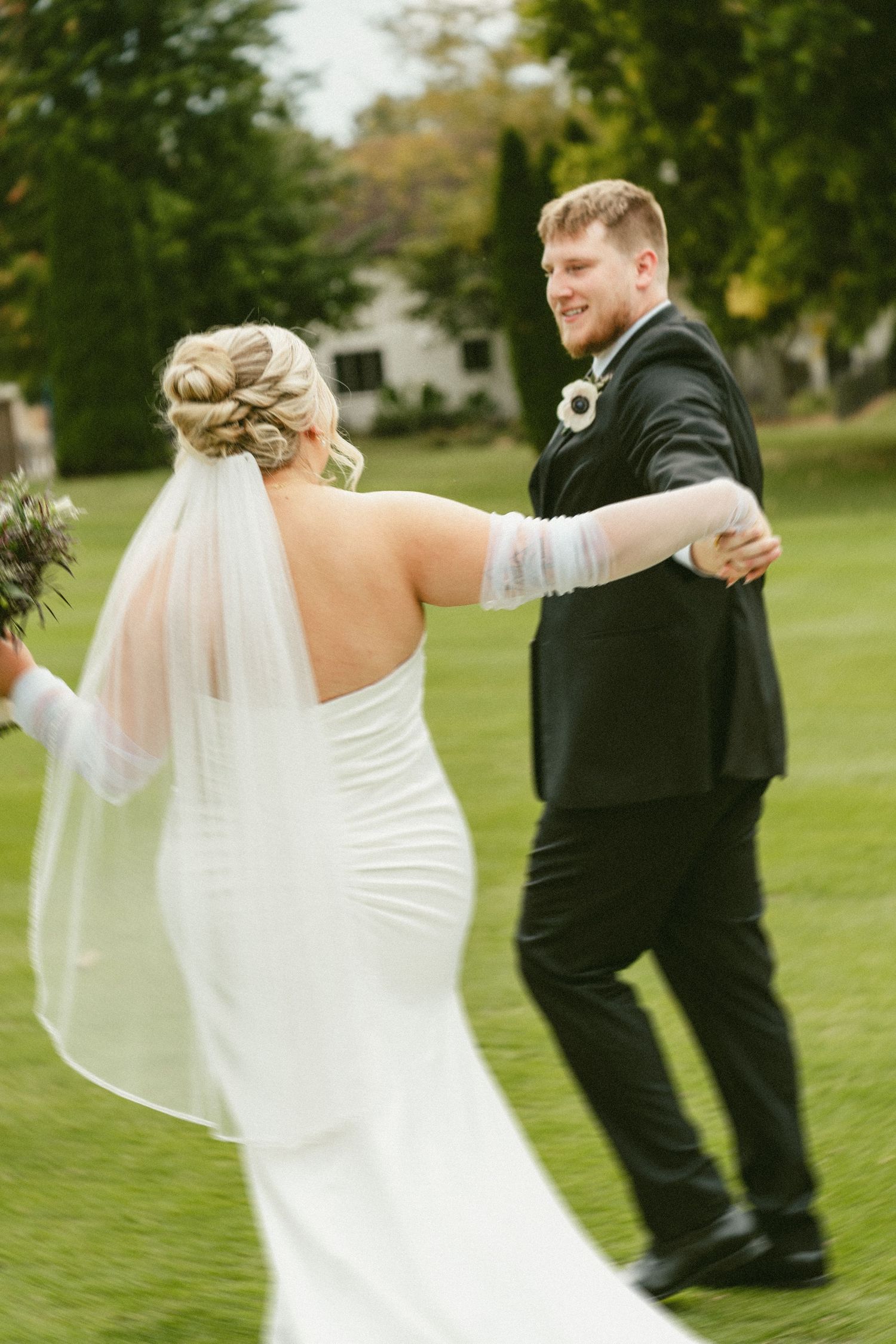 A bride and groom dance together on a lush green lawn during their outdoor wedding celebration. Located in Bellbrook, Ohio.