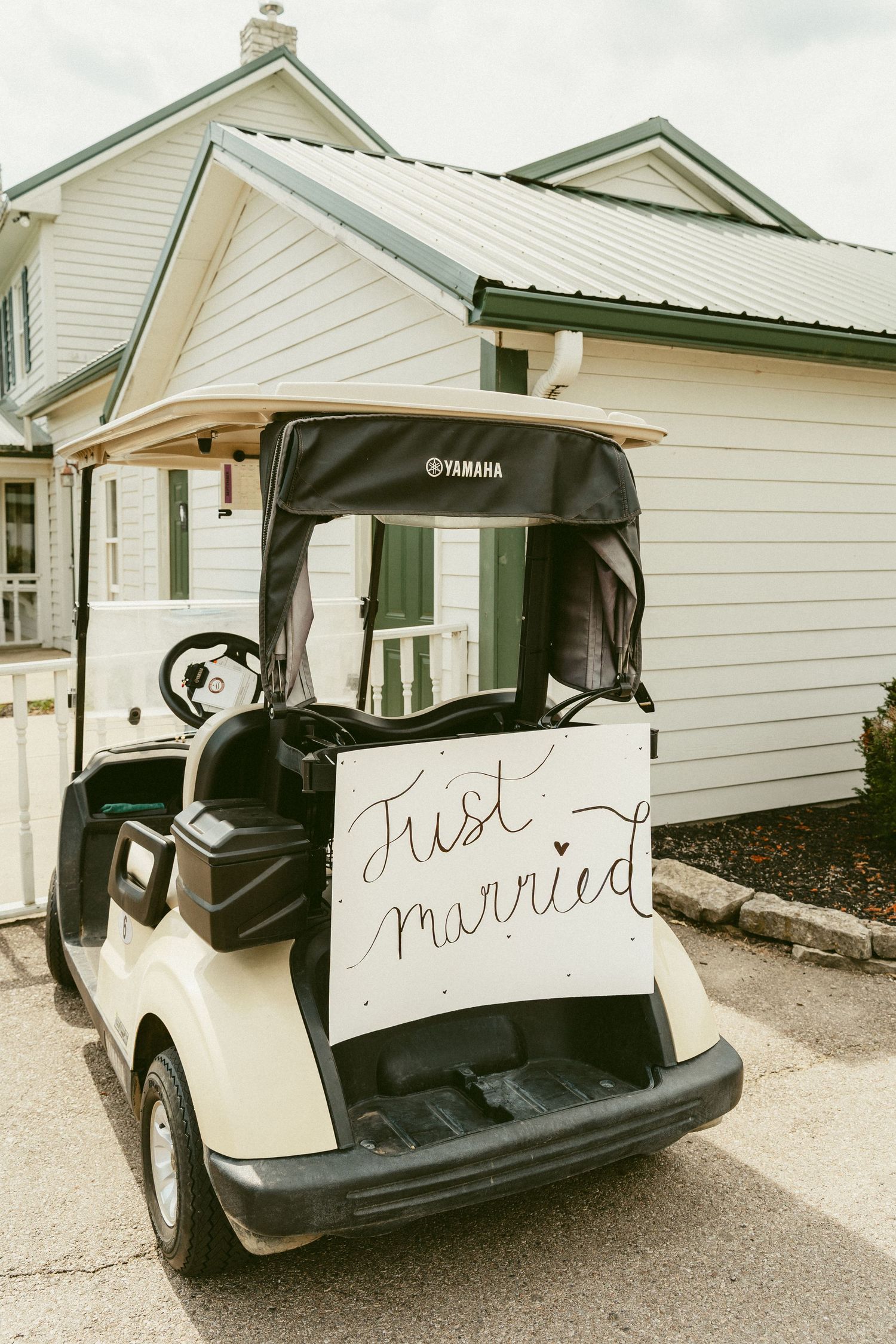 A white Yamaha golf cart decorated with a 'Just Married' sign parked outside a white house. Located in Bellbrook, Ohio.