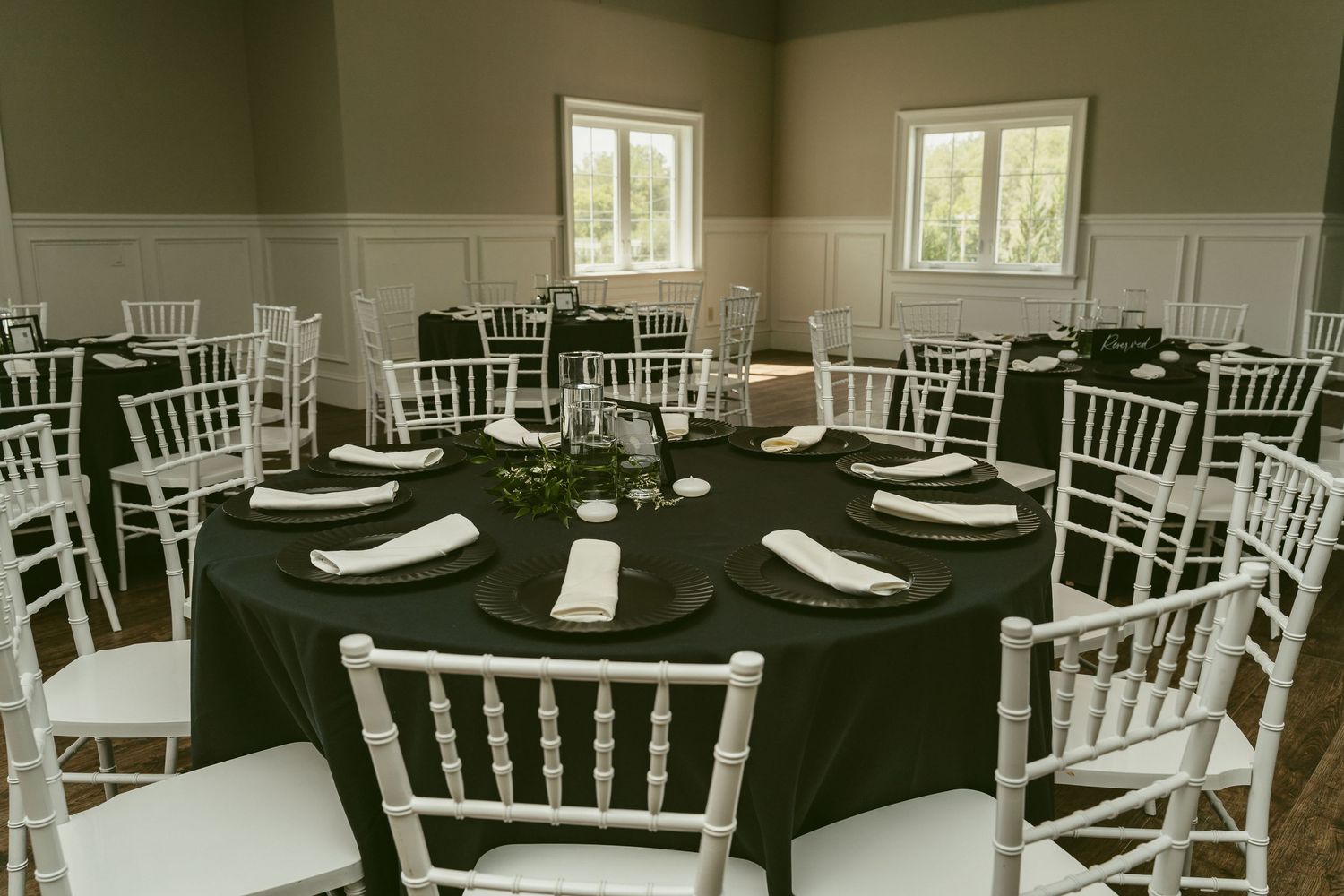 A banquet hall with white Chiavari chairs and black tablecloths set up for an elegant event. Located in Bellbrook, Ohio.