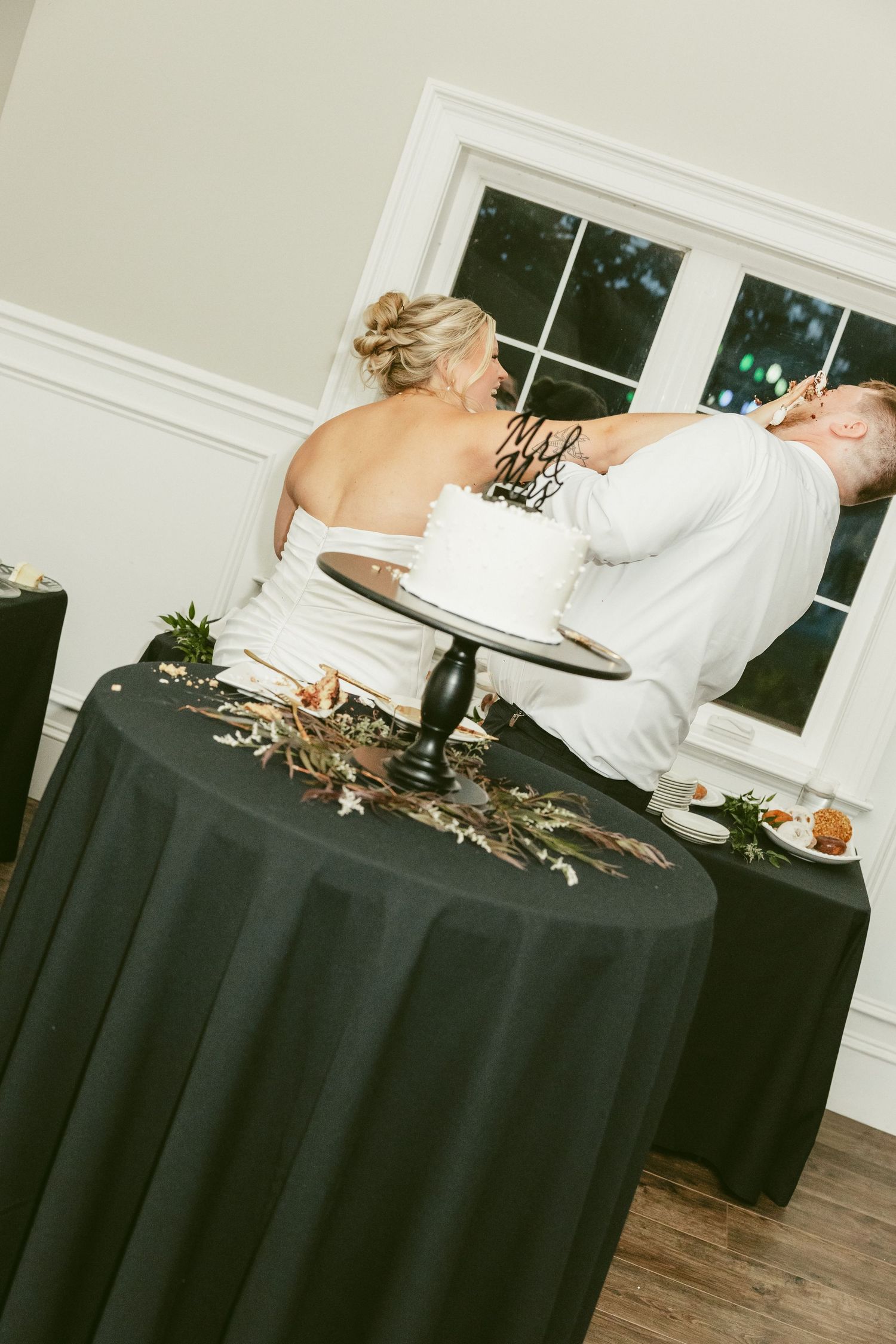 A person in white dress lying dramatically across a round table covered with a black tablecloth. Located in Bellbrook, Ohio.