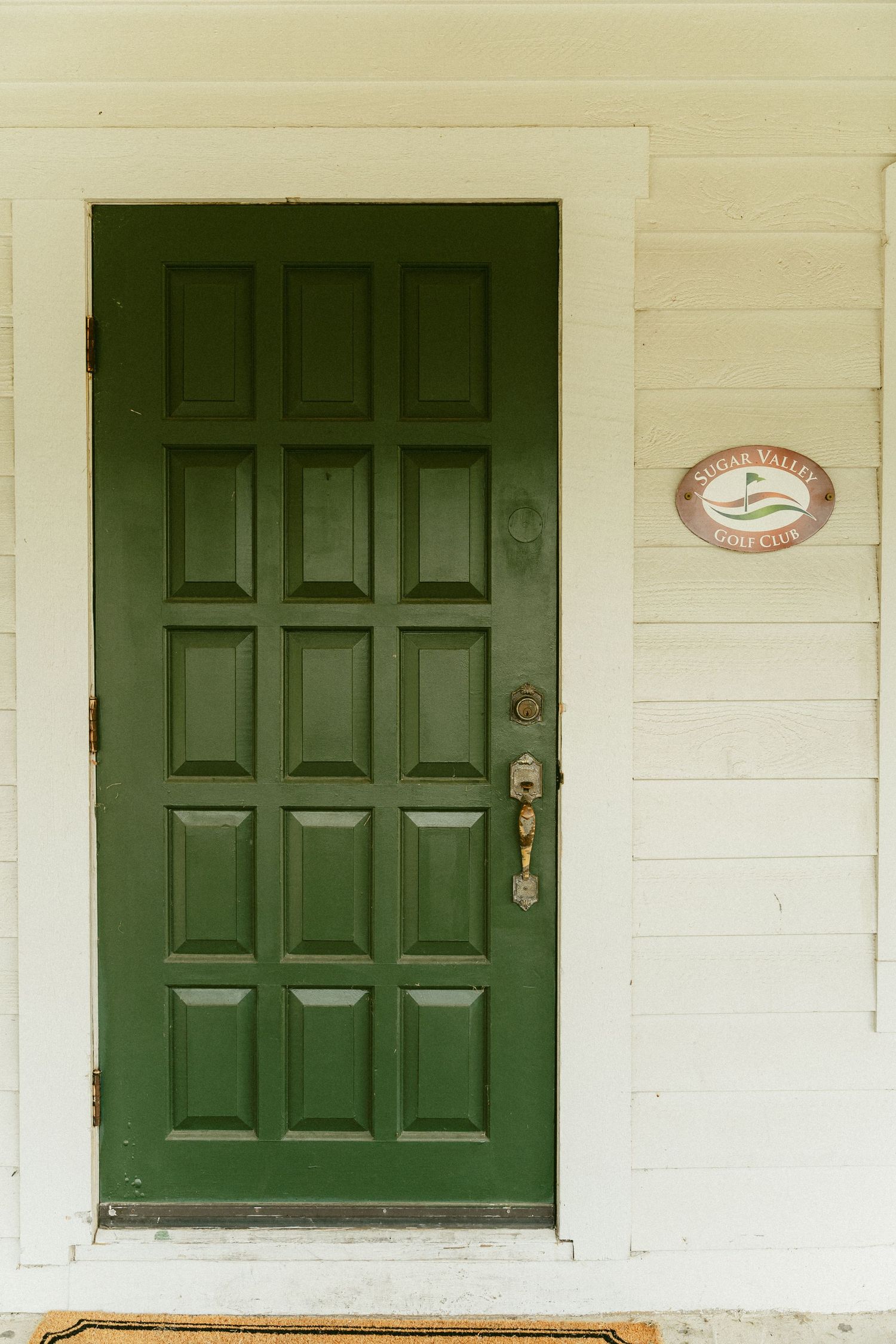 Three dark green wooden doors on a white building exterior with paneled walls and classic colonial style architecture. Located in Bellbrook