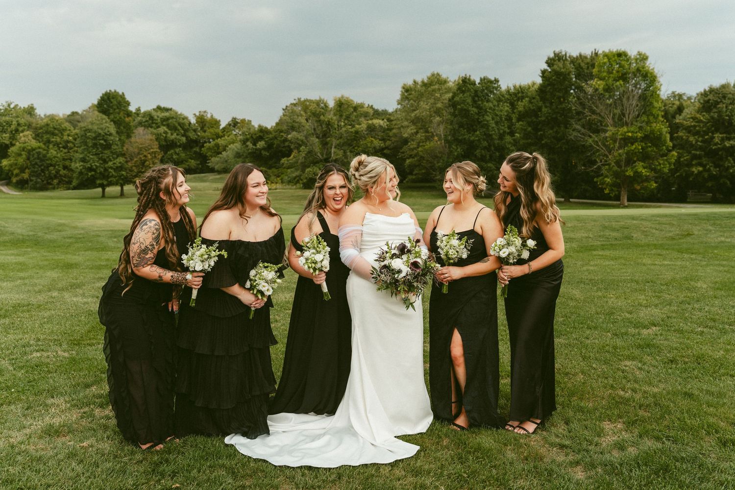 Wedding party poses together on a lush green golf course in black and white dresses. Located in Bellbrook, Ohio.