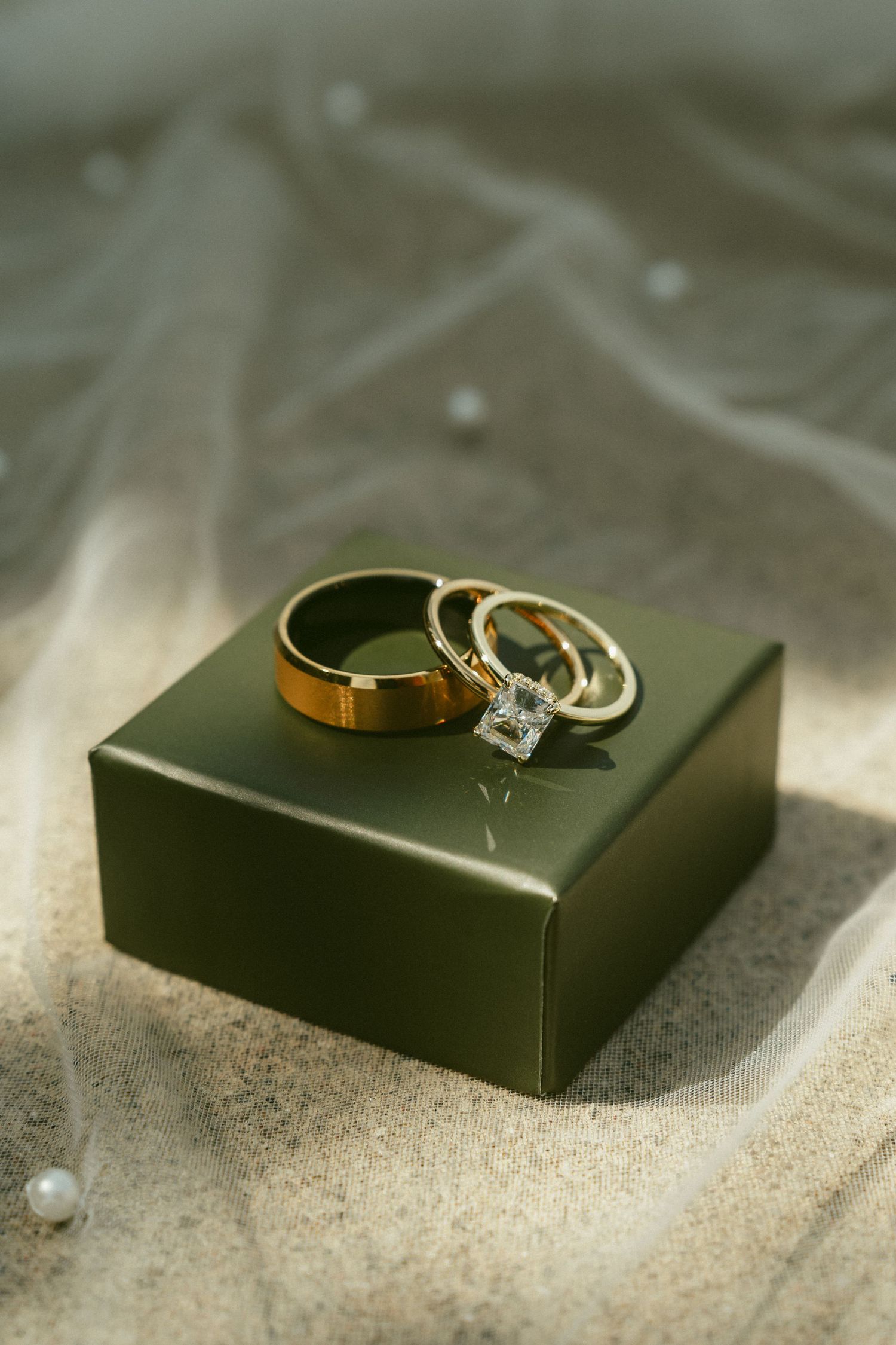 Gold wedding rings and diamond engagement ring rest on black display boxes in soft natural light. Located in Bellbrook, Ohio.