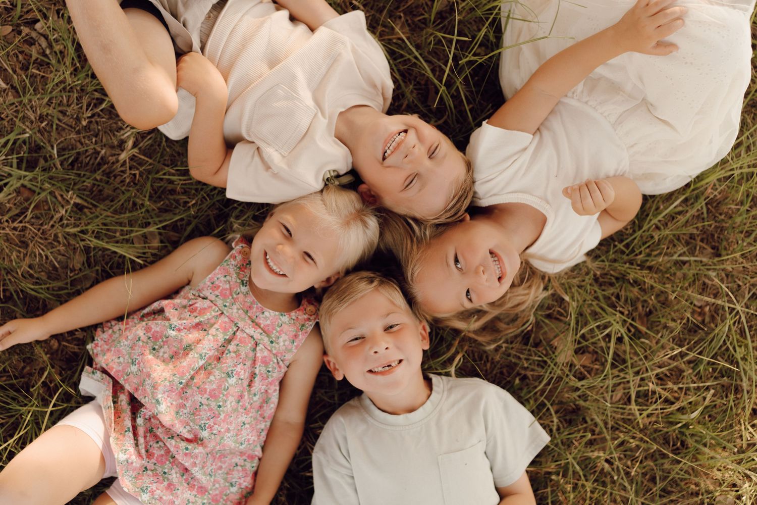Smiling family of four posing outdoors for a family portrait during golden hour.