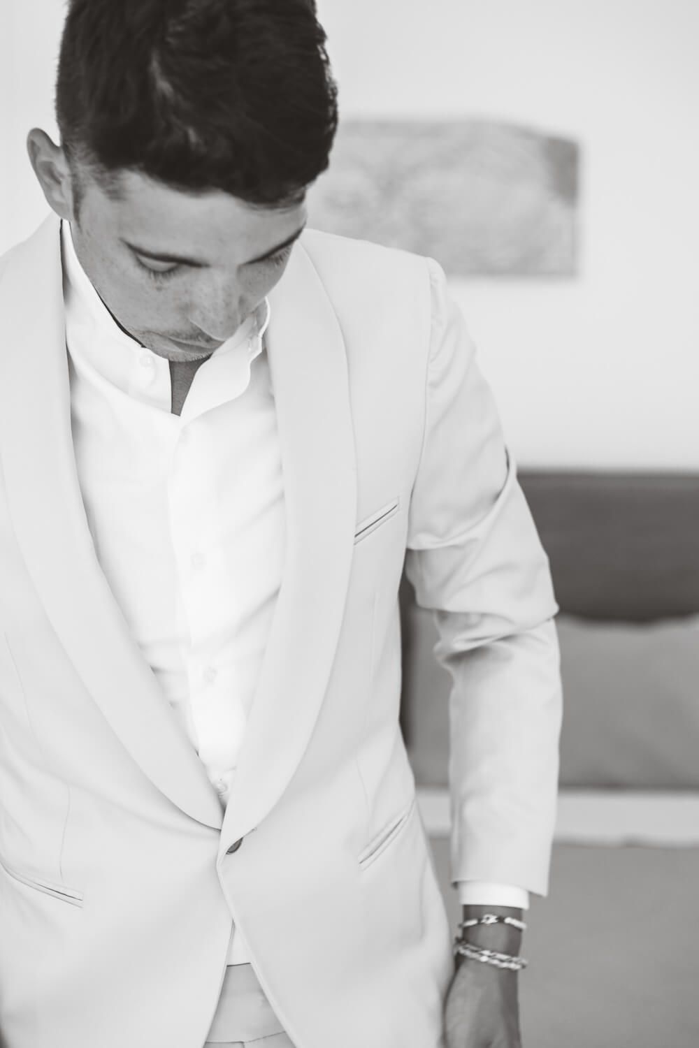 Groom Marco adjusting his bow tie before his destination wedding in Greece