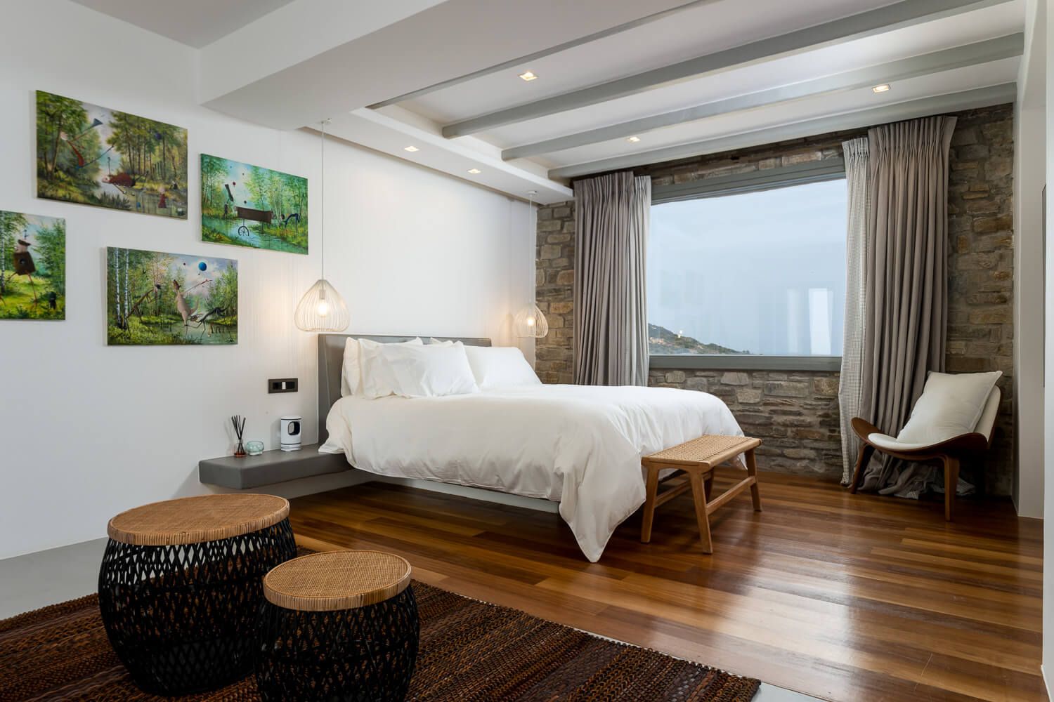 Modern bedroom interior with exposed wood beams, hardwood floors and white bedding in a rustic-contemporary style.