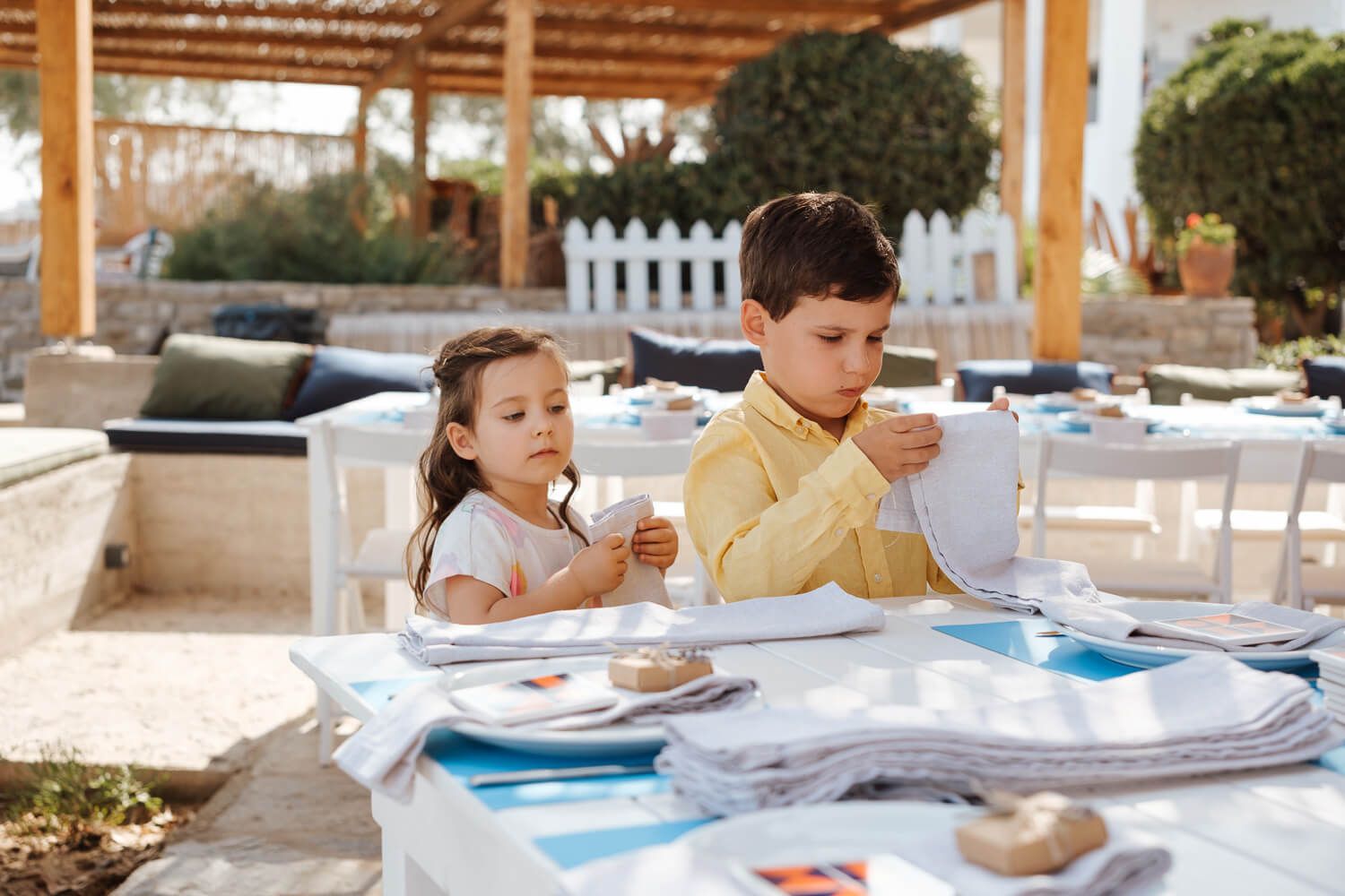 Beautiful wedding reception decor and table settings being prepared by two kids at Rebel Bar Paros
