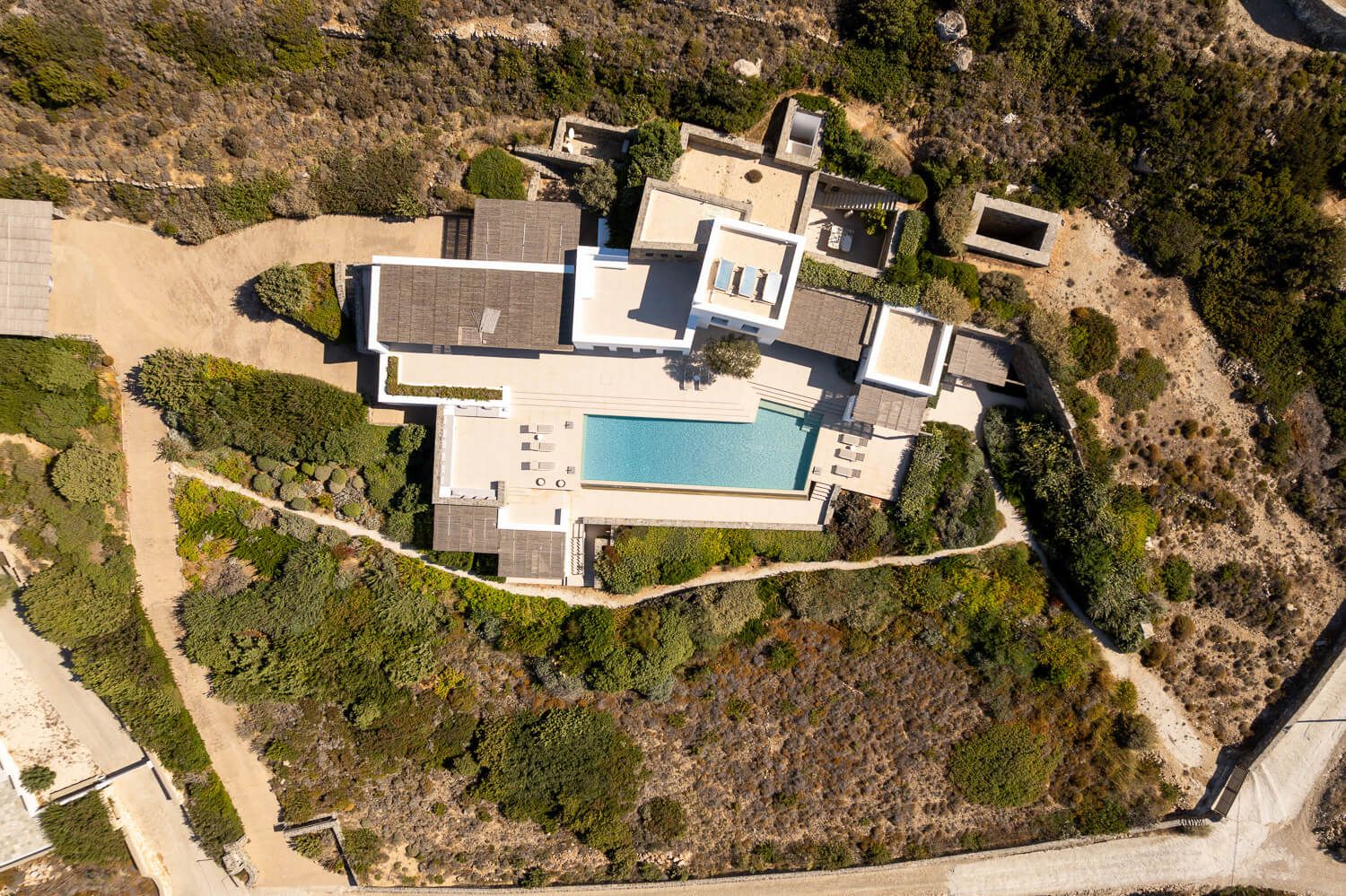 Aerial view of luxury hillside homes with swimming pools overlooking a scenic coastal landscape.