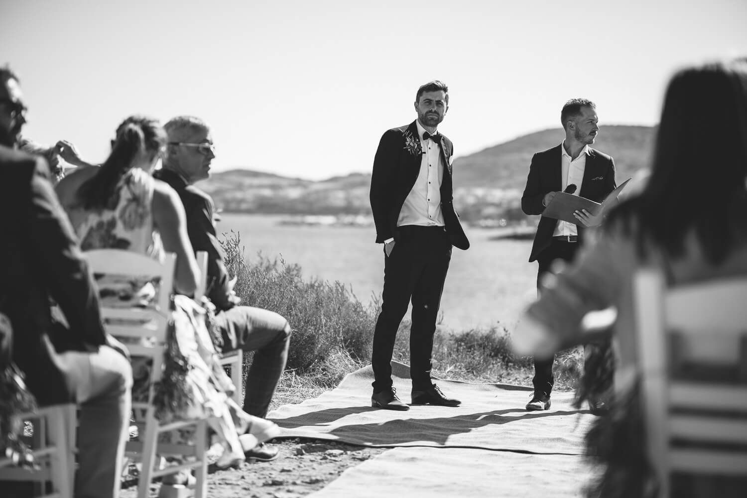Groom waiting by the ocean for his bride to arrive in Greece