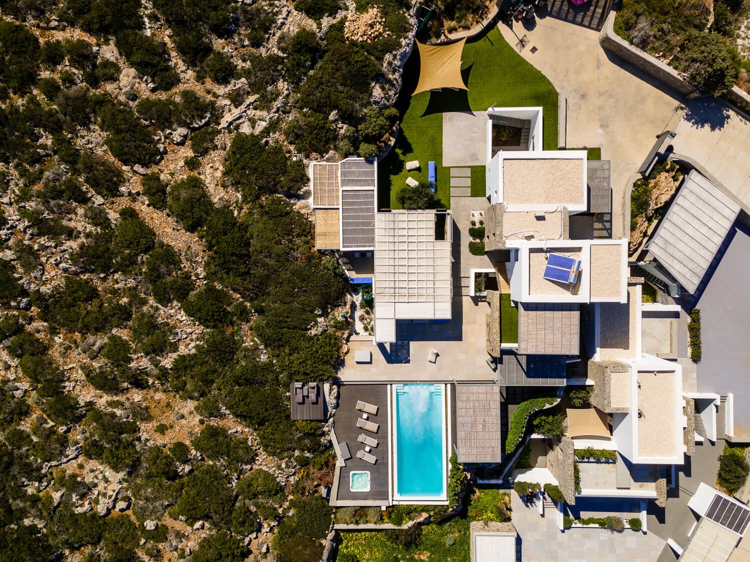 Aerial view of modern luxury villa with swimming pools in an arid desert landscape.