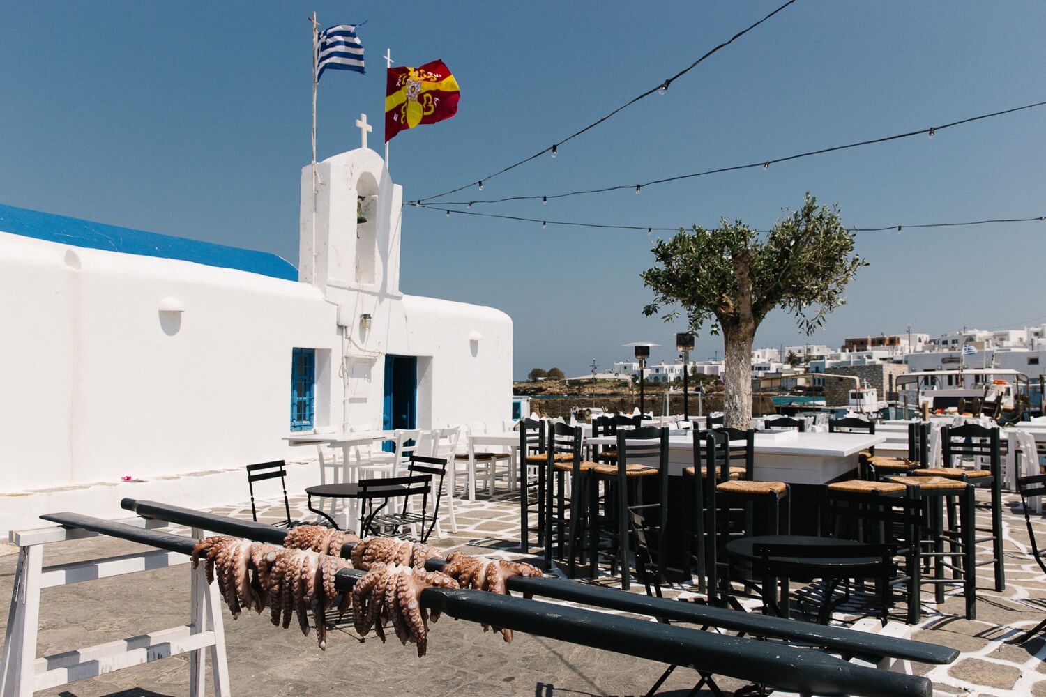 Απλωμένα χταπόδια μπροστά από το εστιατόριο Barbarossa με φόντο τον Άγιο Νικόλαο στο λιμανάκι της Νάουσας στην Πάρο.