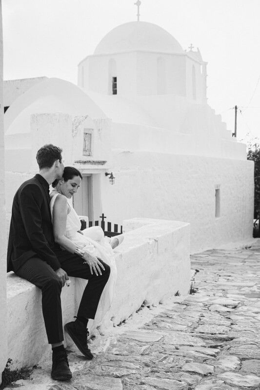 Couple sitting together on whitewashed steps near a Greek Orthodox church in Amorgos.