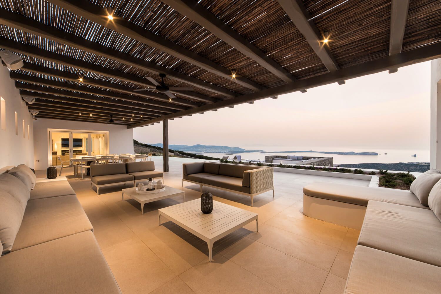Modern minimalist exterior design of a luxury villa with white furniture and bamboo ceiling details.