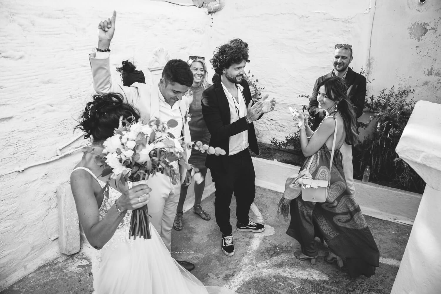 Happy Erika and Marco walking out of the church as guests throw rice and petals