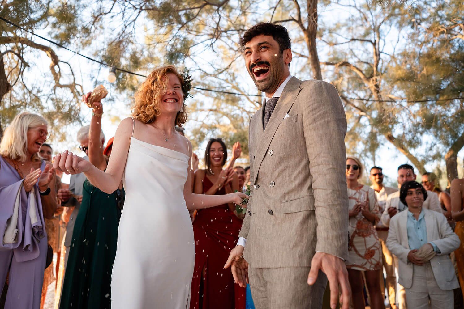Happy guests throwing rose petals at a seaside destination wedding