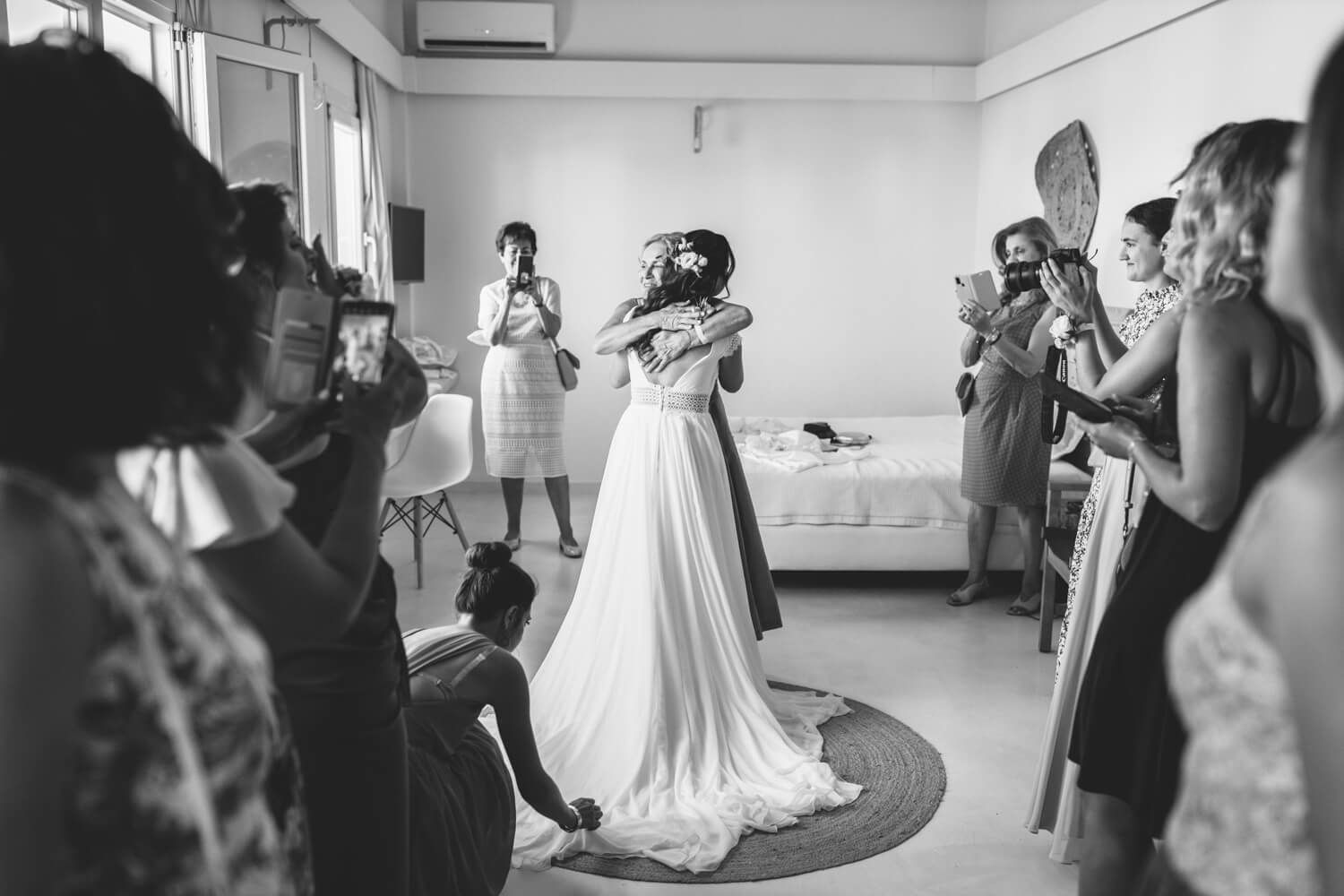 Bride in white wedding dress twirling during indoor wedding celebration with guests taking photos.