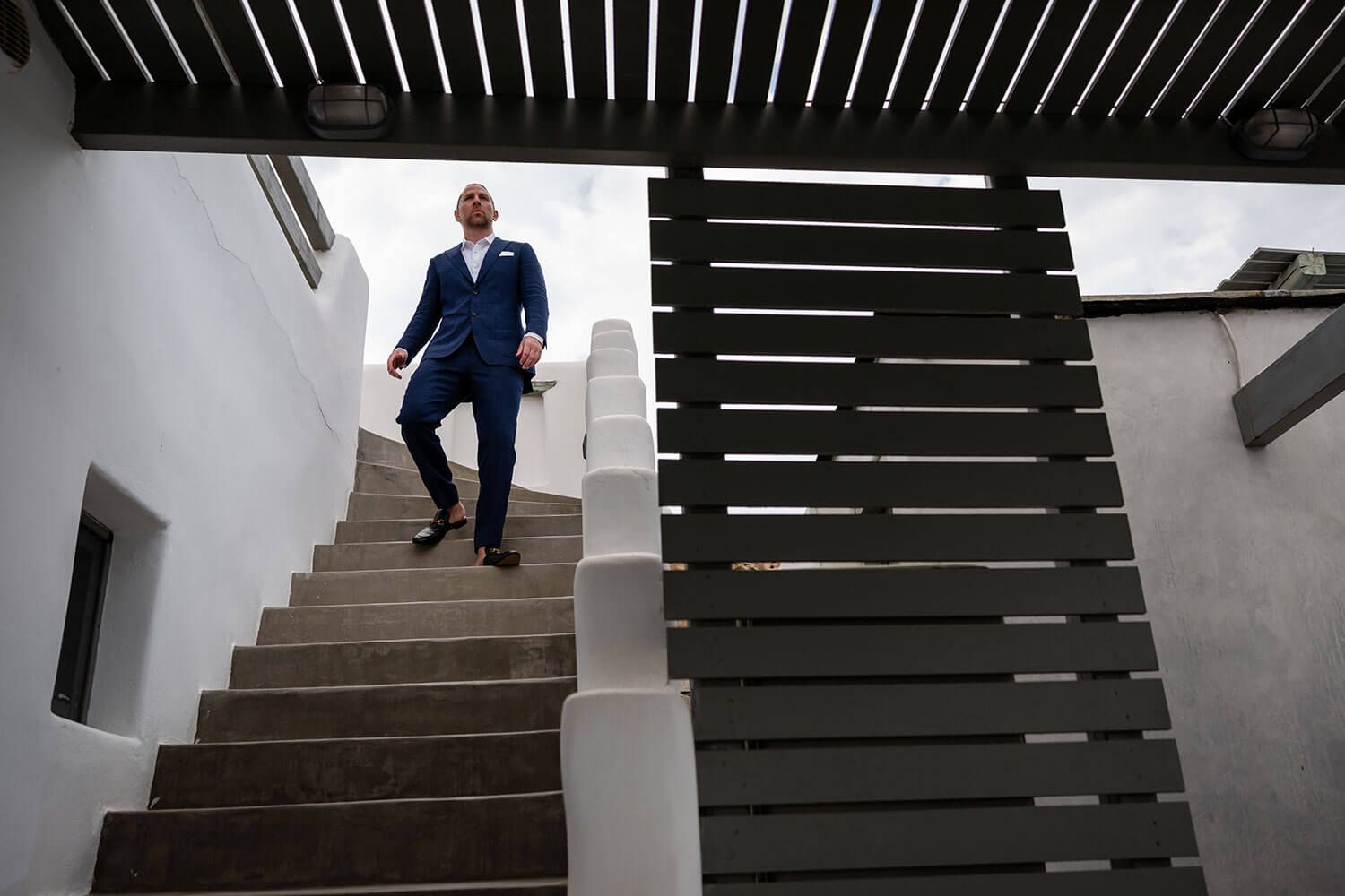 Groom walking down the stairs of a traditional Cycladic villa