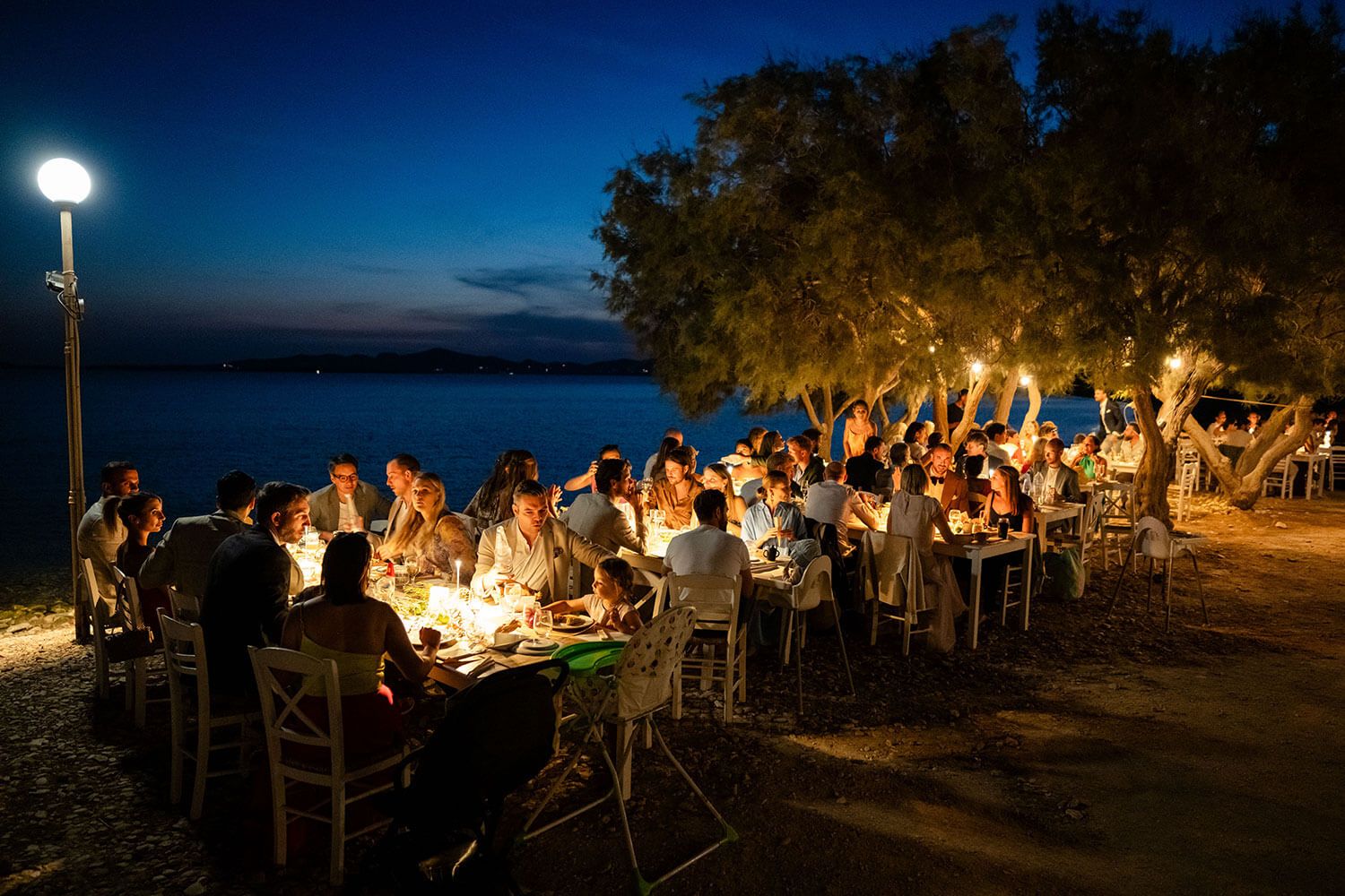 Guests enjoying a seaside wedding reception under the stars in Aliki