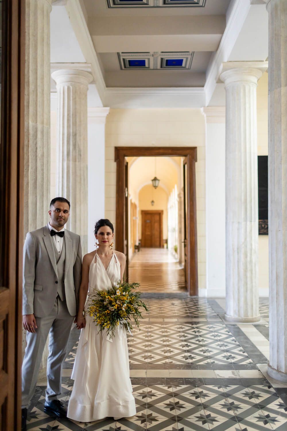 The couple holding hands under the beautiful town hall arches