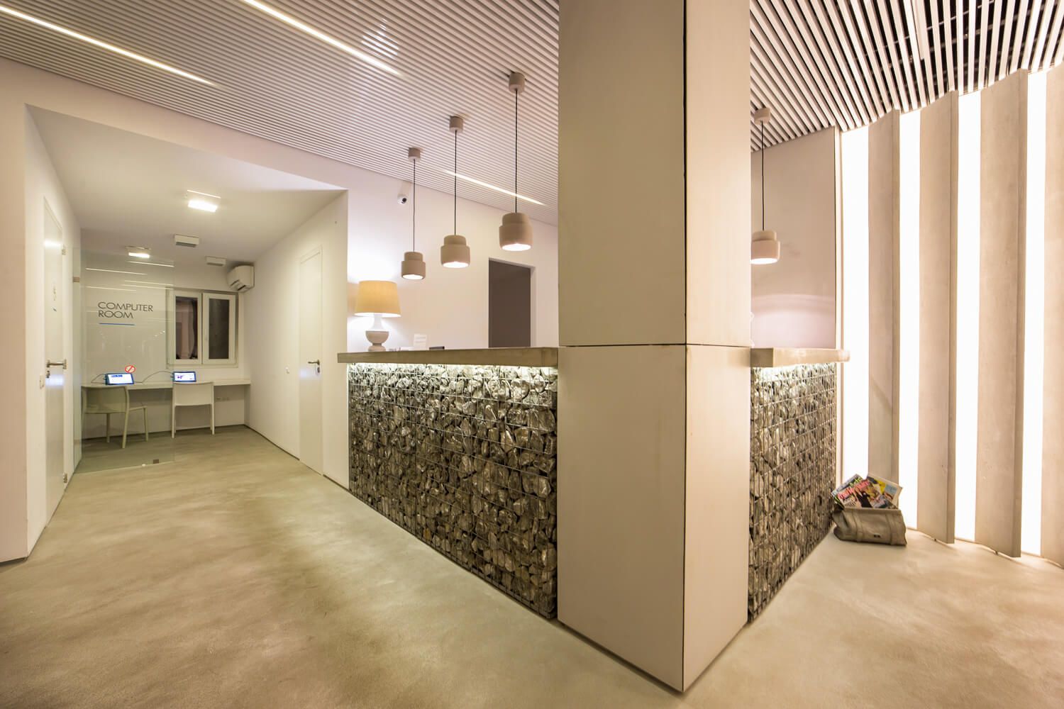 Modern hotel reception corridor with white walls, pendant lighting, and wood-slat ceiling design features sleek architectural details.