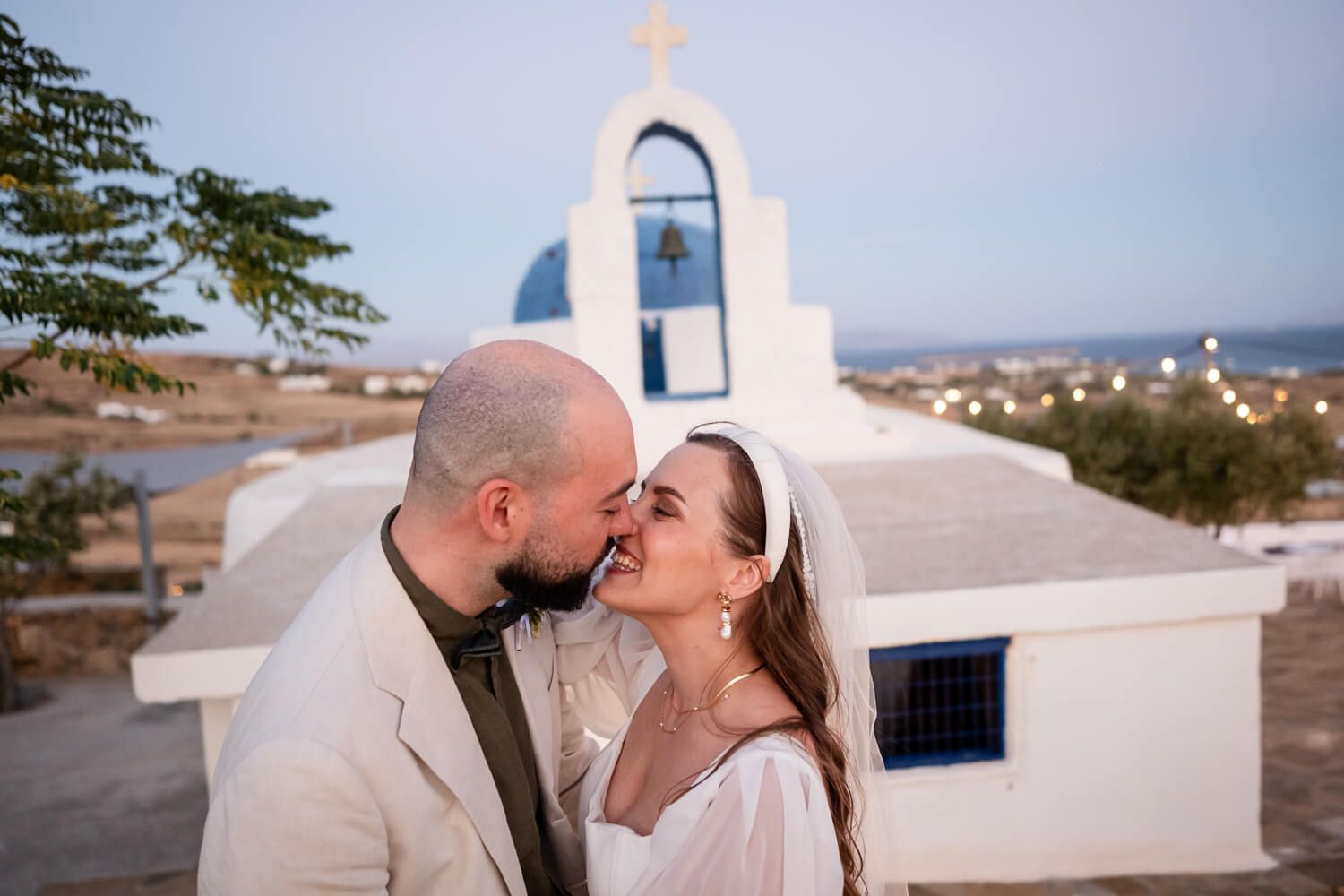Bride and groom kissing in front of a chapel at the Secret View Venue in Paros Island.