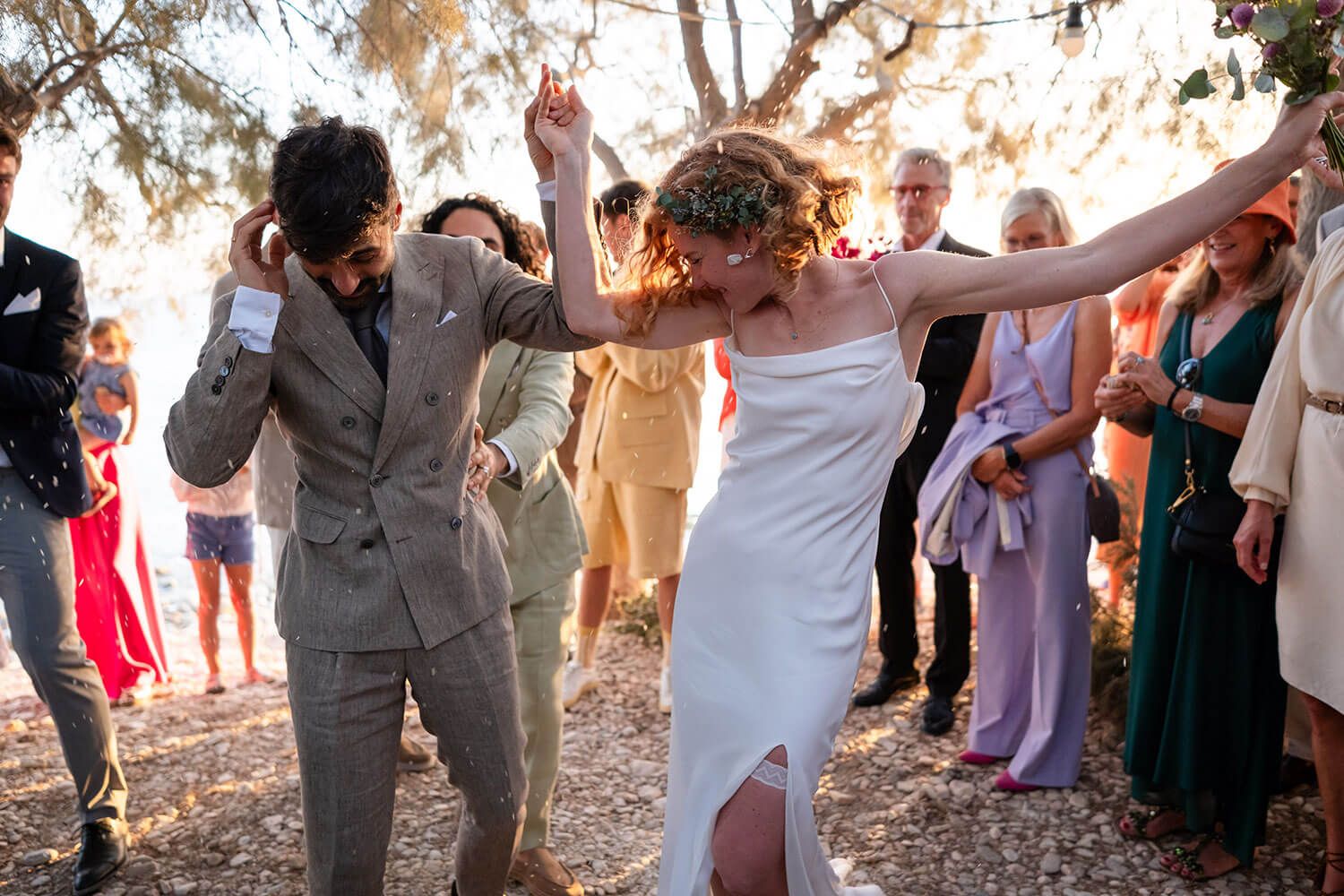 Happy guests throwing rose petals at a seaside destination wedding