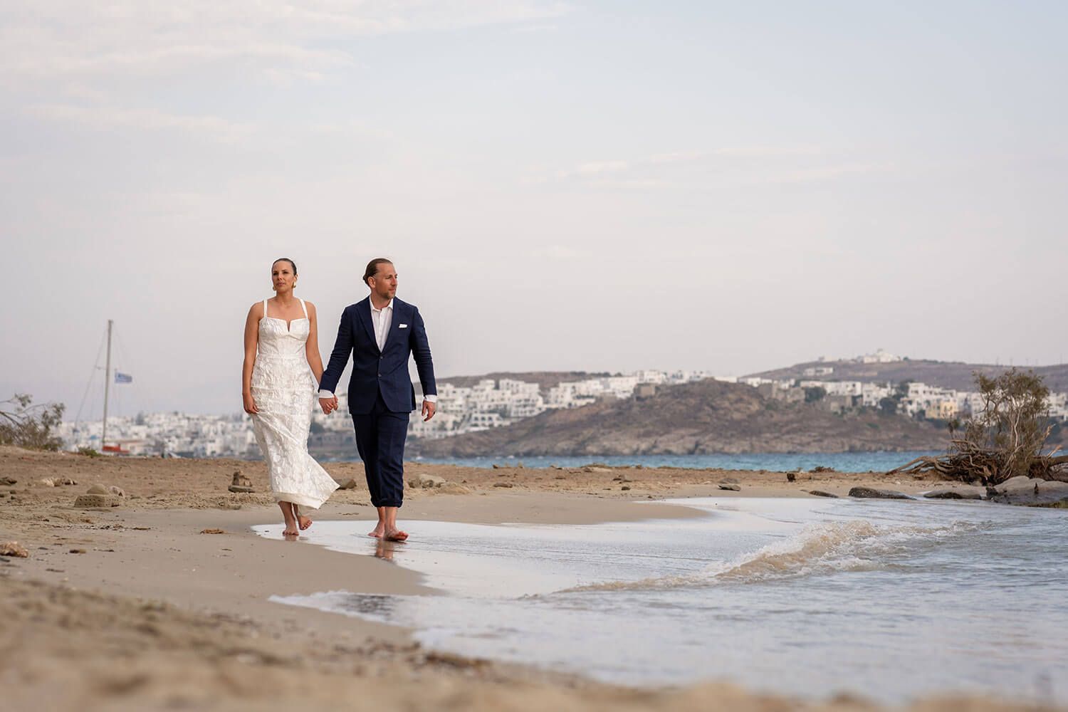 Newlyweds walking holding hands on the famous rocks of Kolimbithres beach