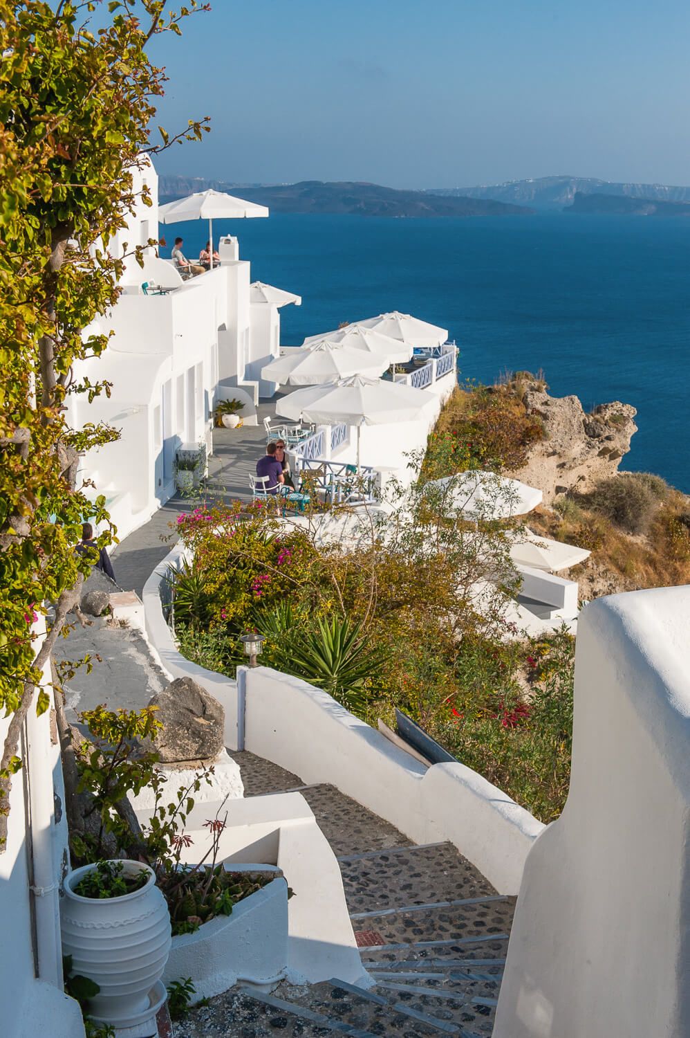 Sunlit exterior corridors leading to luxury suites in Santorini