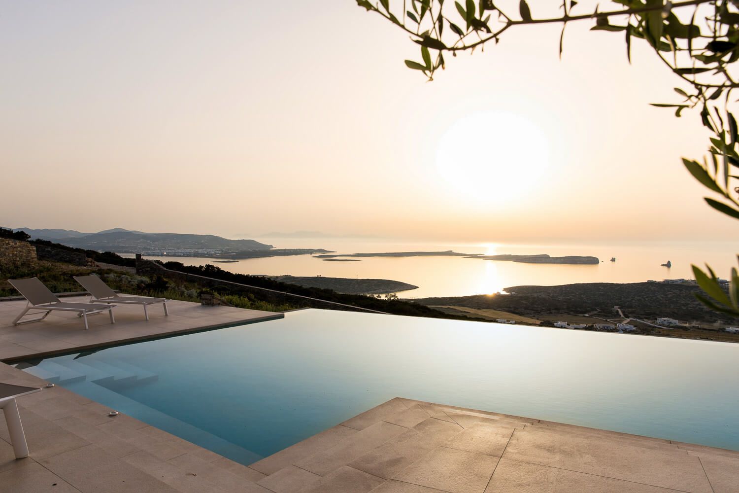 Pool overlooking a stunning Greek island sunset with panoramic sea views and tranquil golden sky.