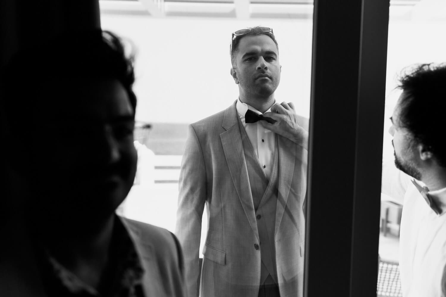 Groom tying his bowtie in a beautiful traditional Syros house
